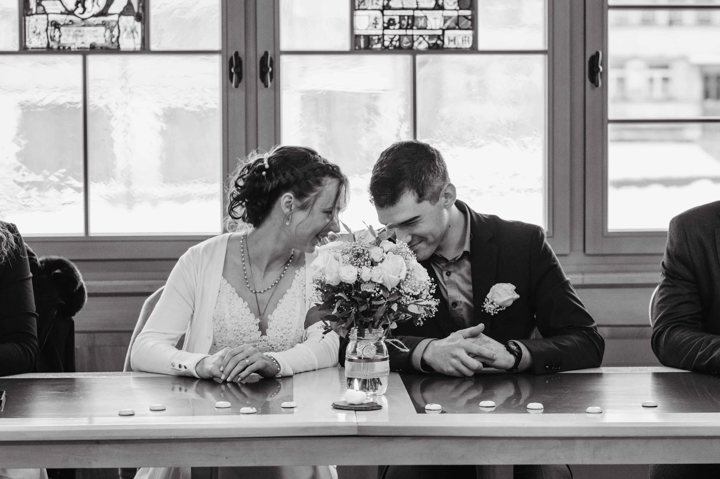 Ein Brautpaar bei einer standesamtlichen Zeremonie, sie lachen und schauen sich an.