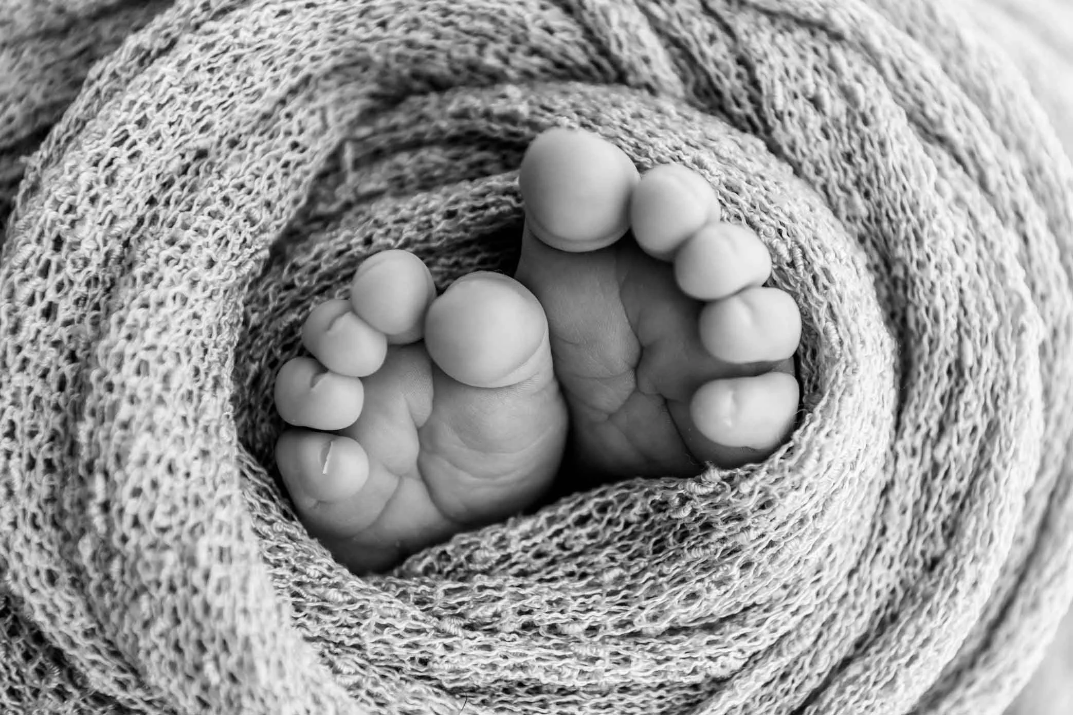 Nahaufnahme von neugeborenen Füsen in Schwarz-Weiss.
