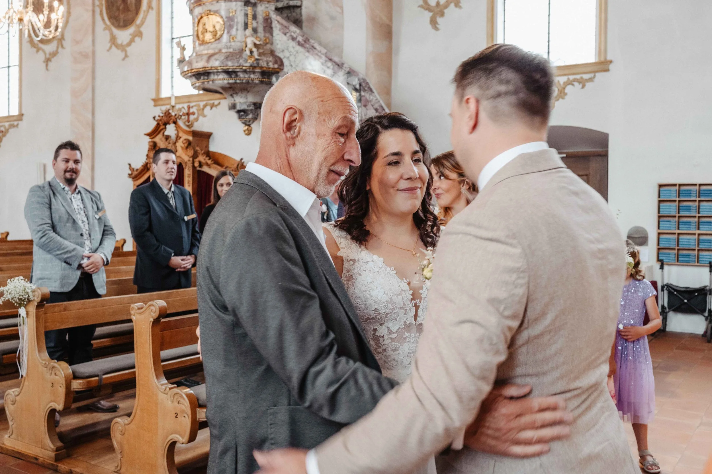 Bräutigam begrüsst seine Braut und Brautvater in der Kirche nach dem Einzug.