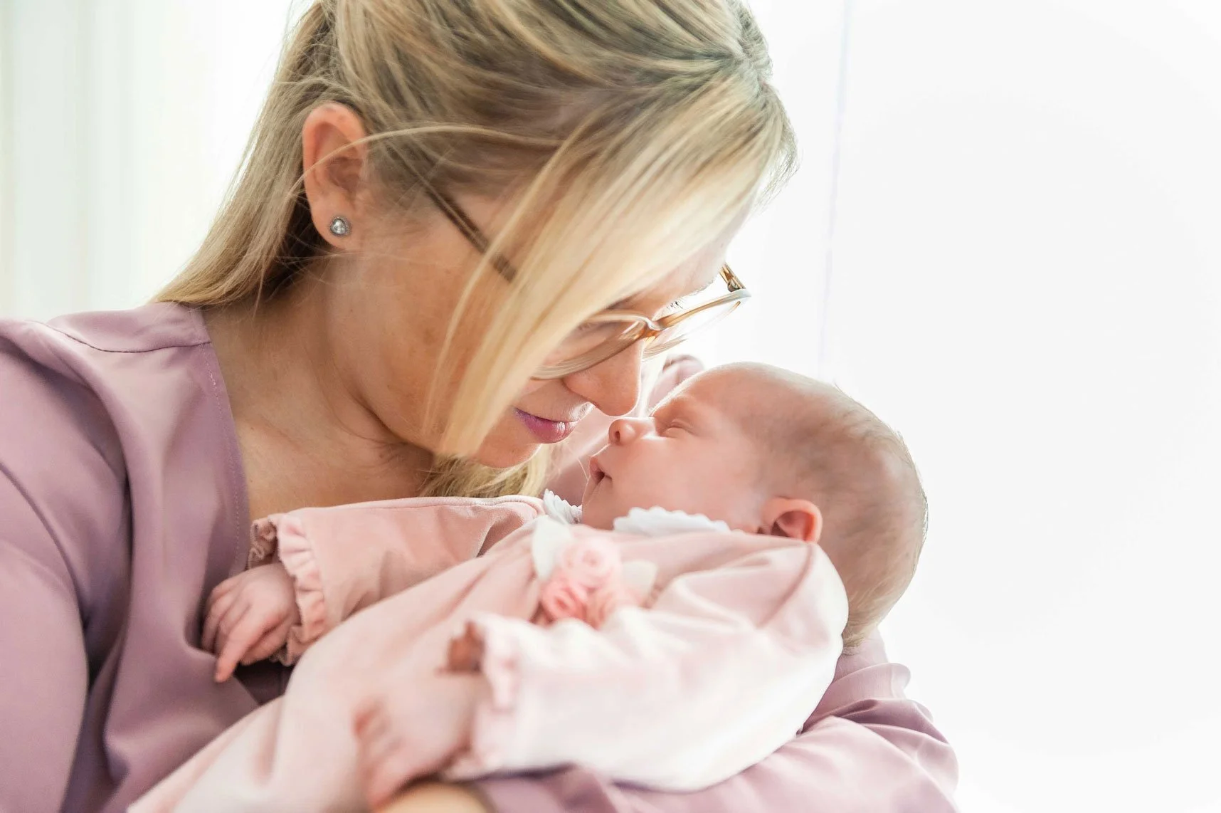 Mama hält ihr neugeborenes in den Armen und beide schauen sich liebevoll an.