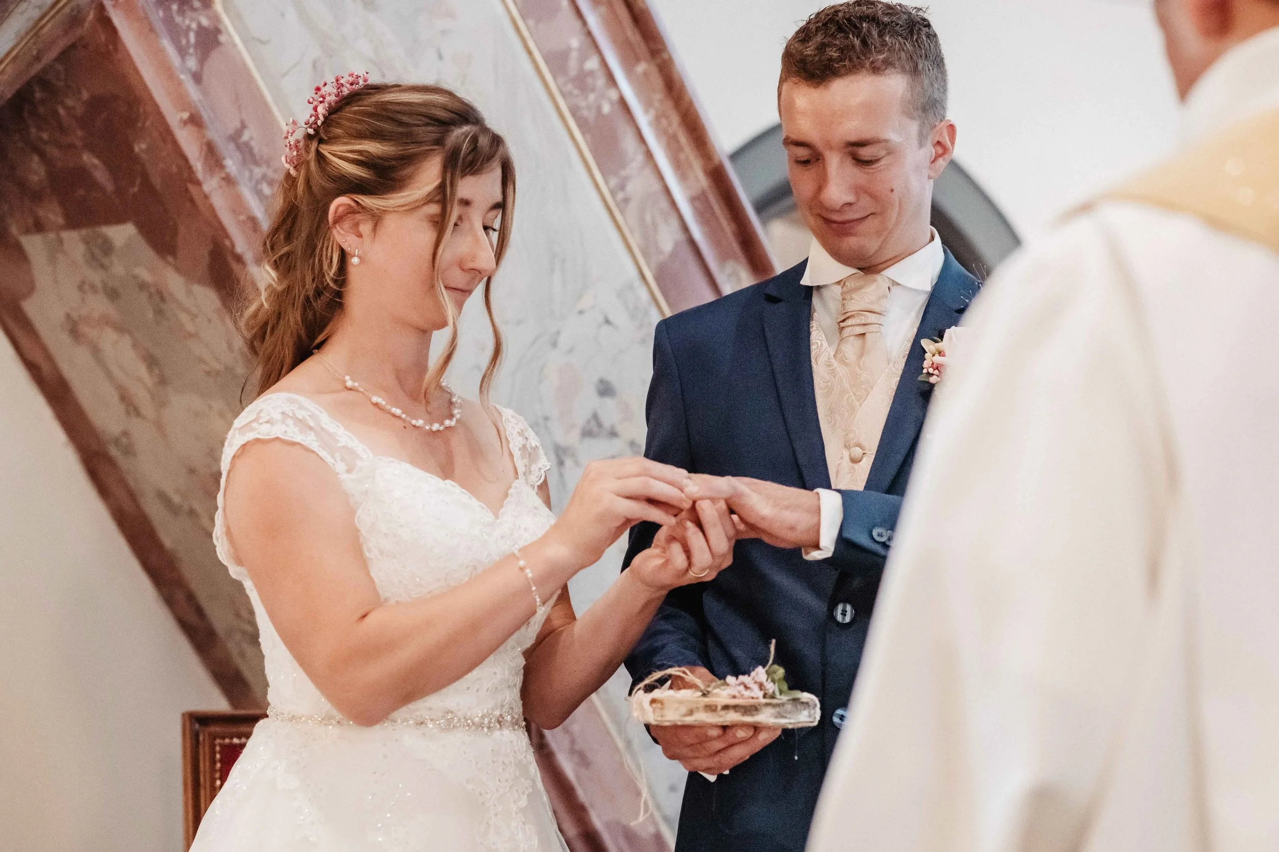 Braut und Bräutigam bei der Eheschliessung, die Braut legt den Ehering auf die Hand des Bräutigams bei einer Hochzeitszeremonie in einem festlichen Raum.