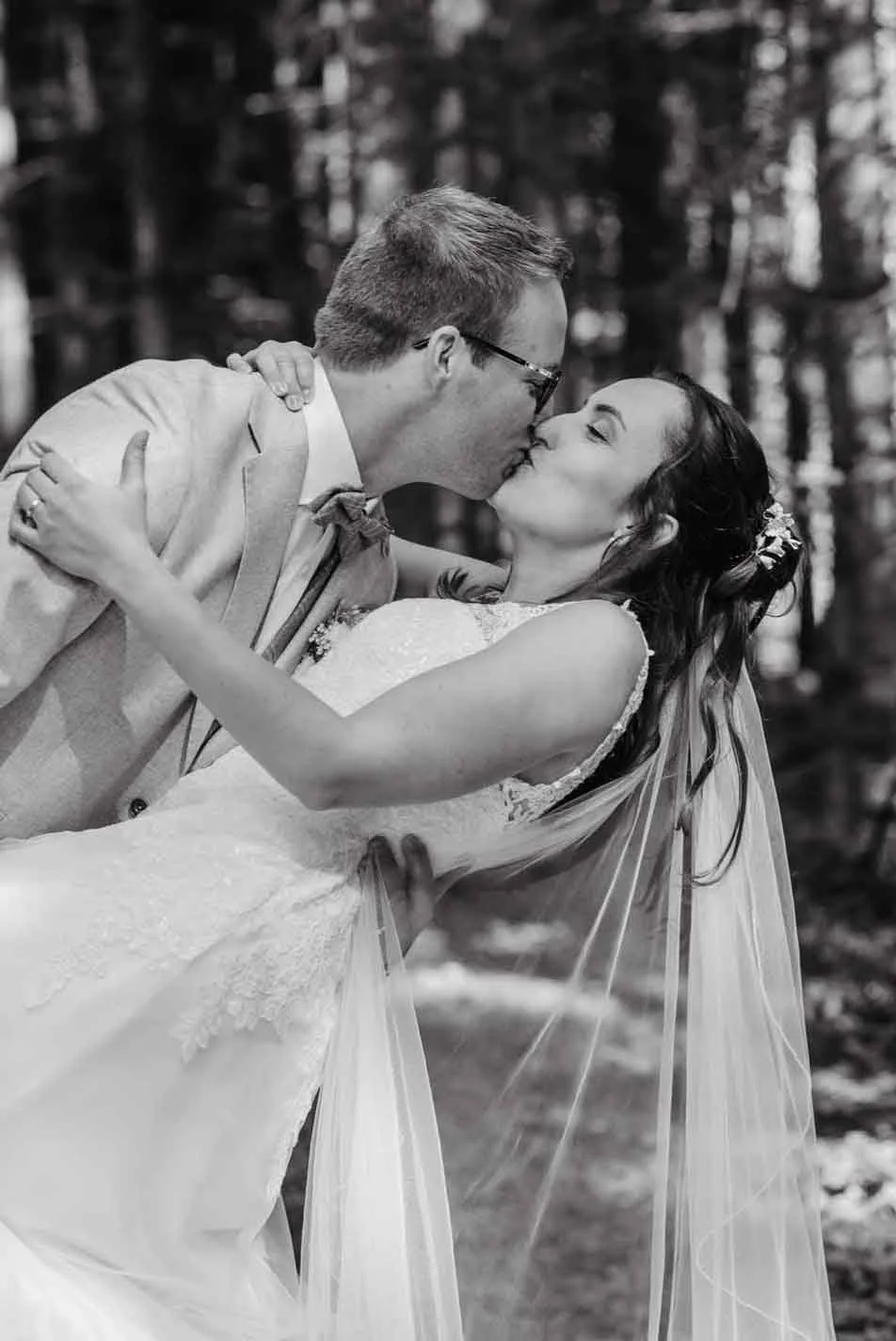 Ein Brautpaar beim Kuss im Wald, schwarz-weiss