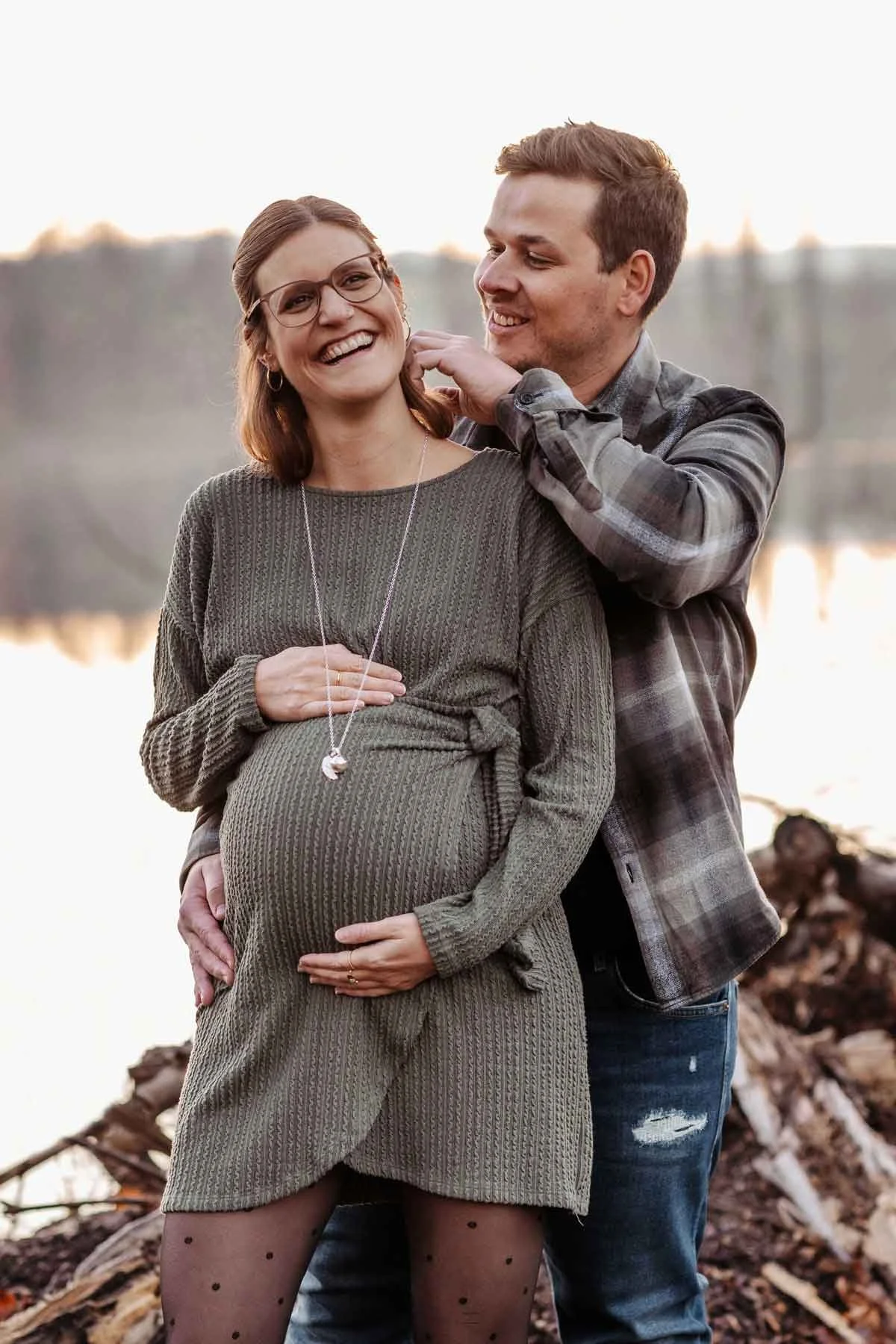 Ein glückliches Paar, schwangere Frau, Sonnenuntergang im Hintergrund.