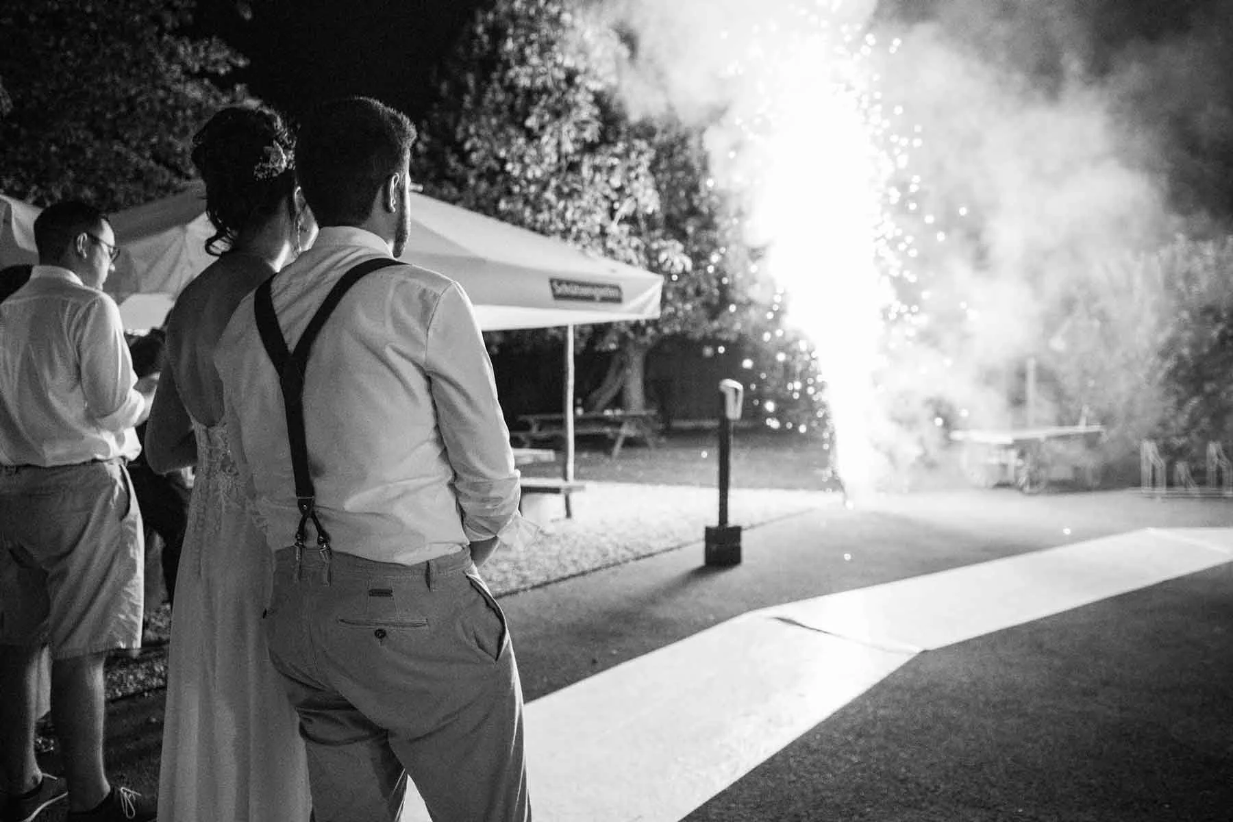 Menschen beobachten bei einer Hochzeit eine Feuerwerk bei Nacht.