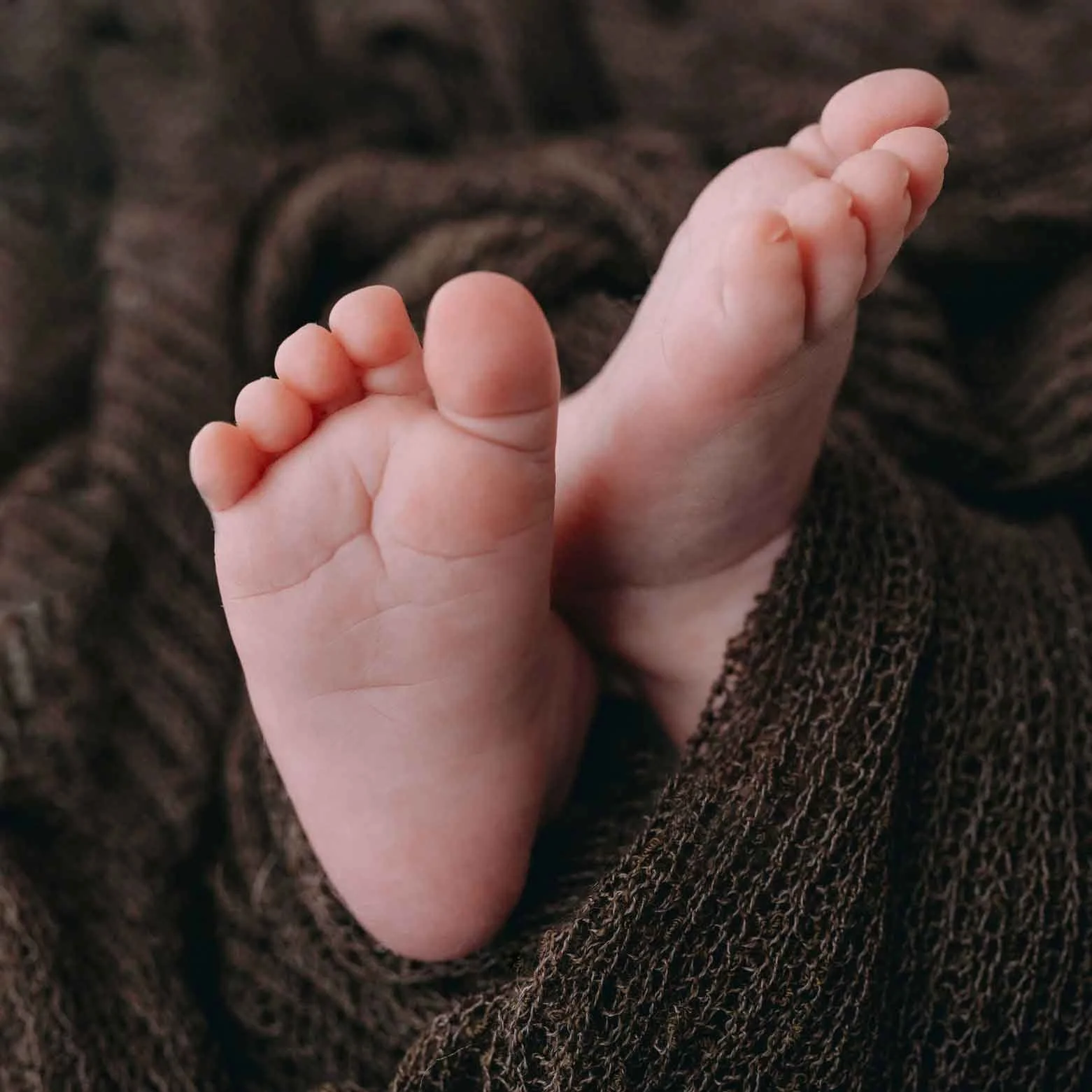 Nahaufnahme eines Babyfusses auf braunem Stoff