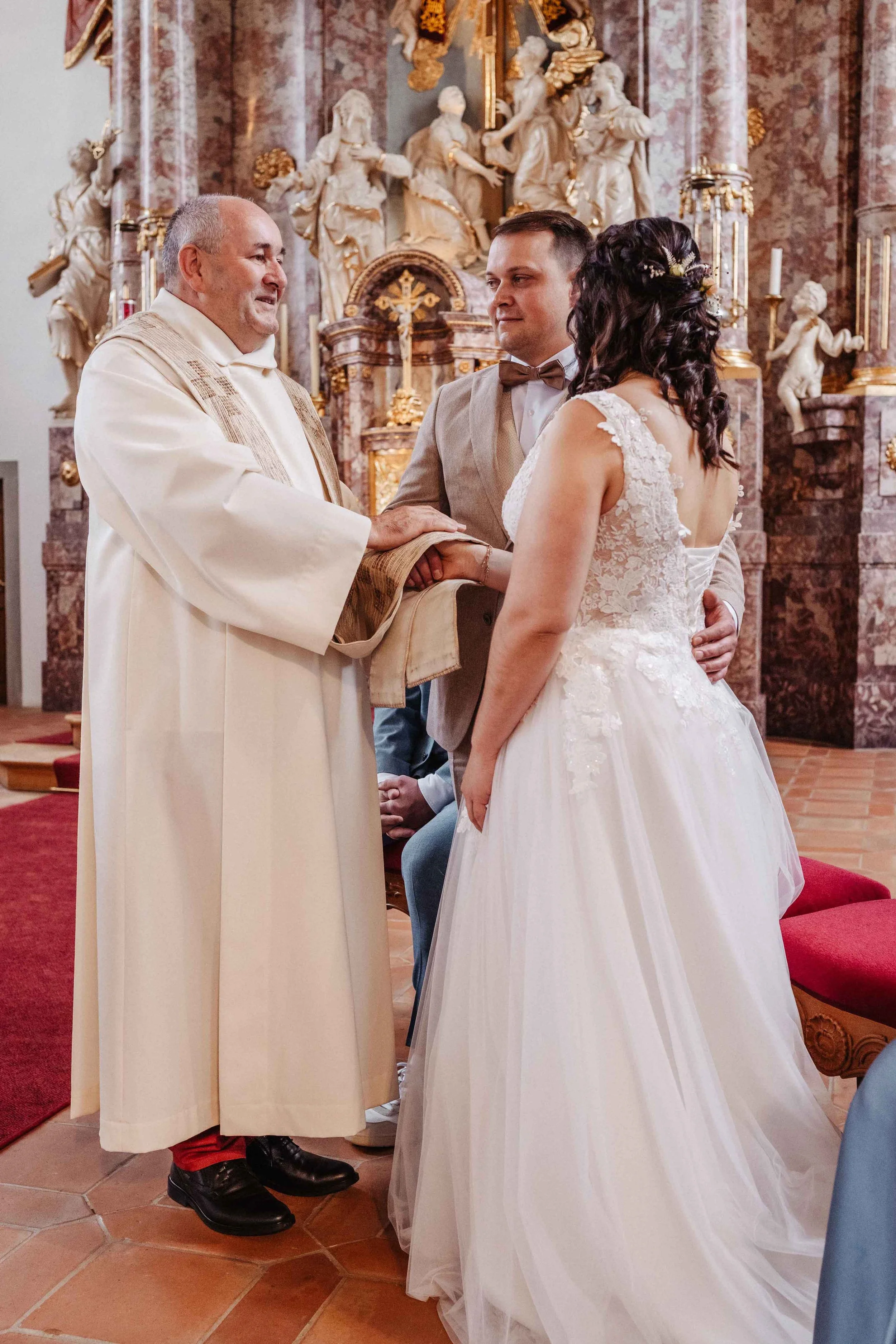 Brautpaar wird in der Kirche während der Hochzeit vom Priester gesegnet.
