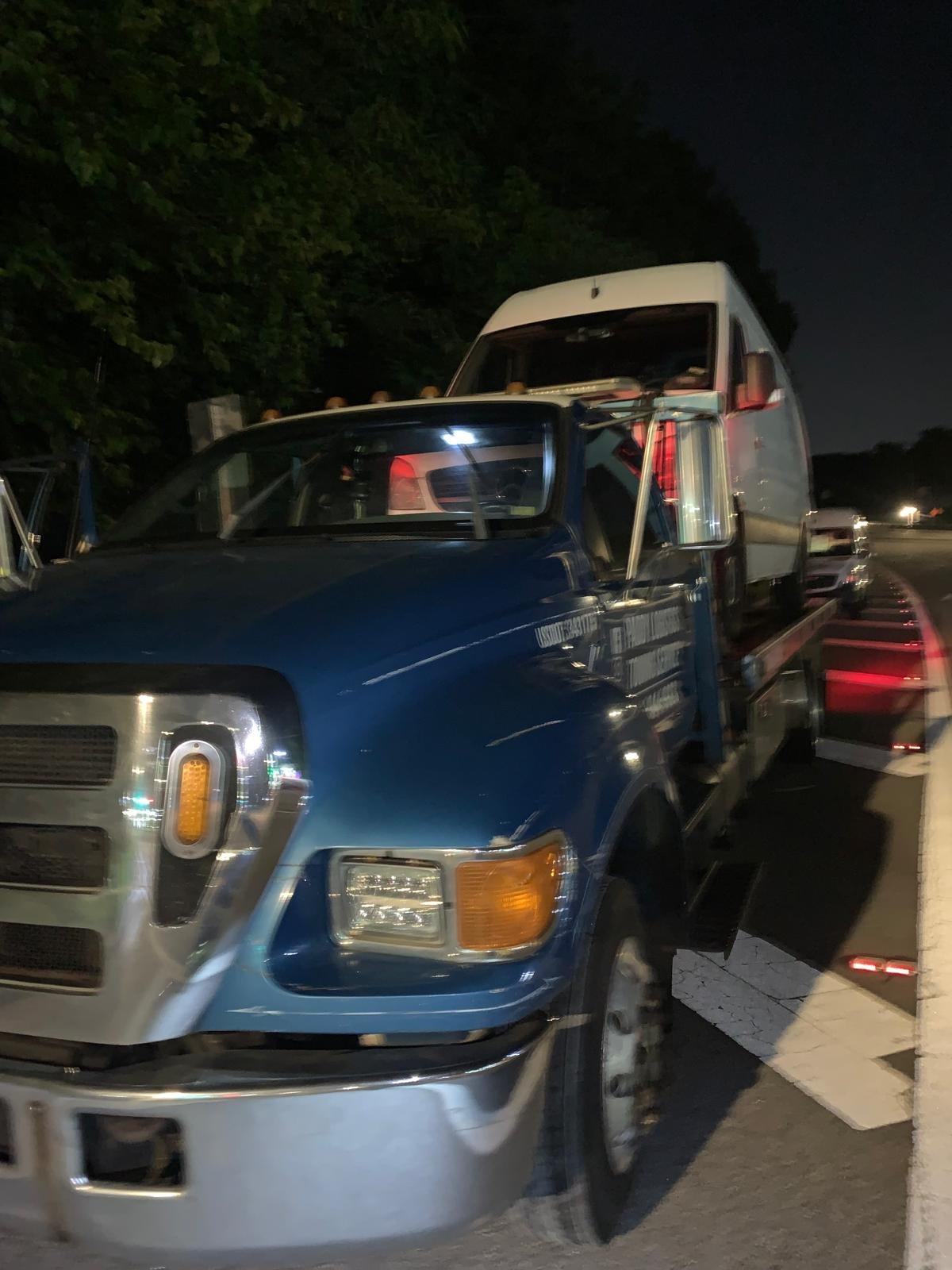 Blue Paddy Logistics semi-truck towing a white box trailer at night