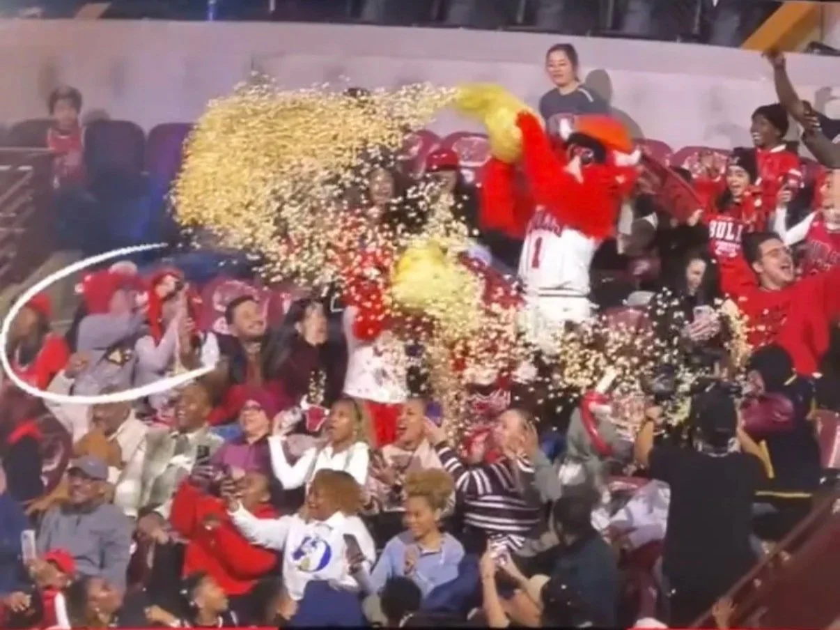 Chicago Bulls player celebrating with fans, surrounded by confetti at a sports event.