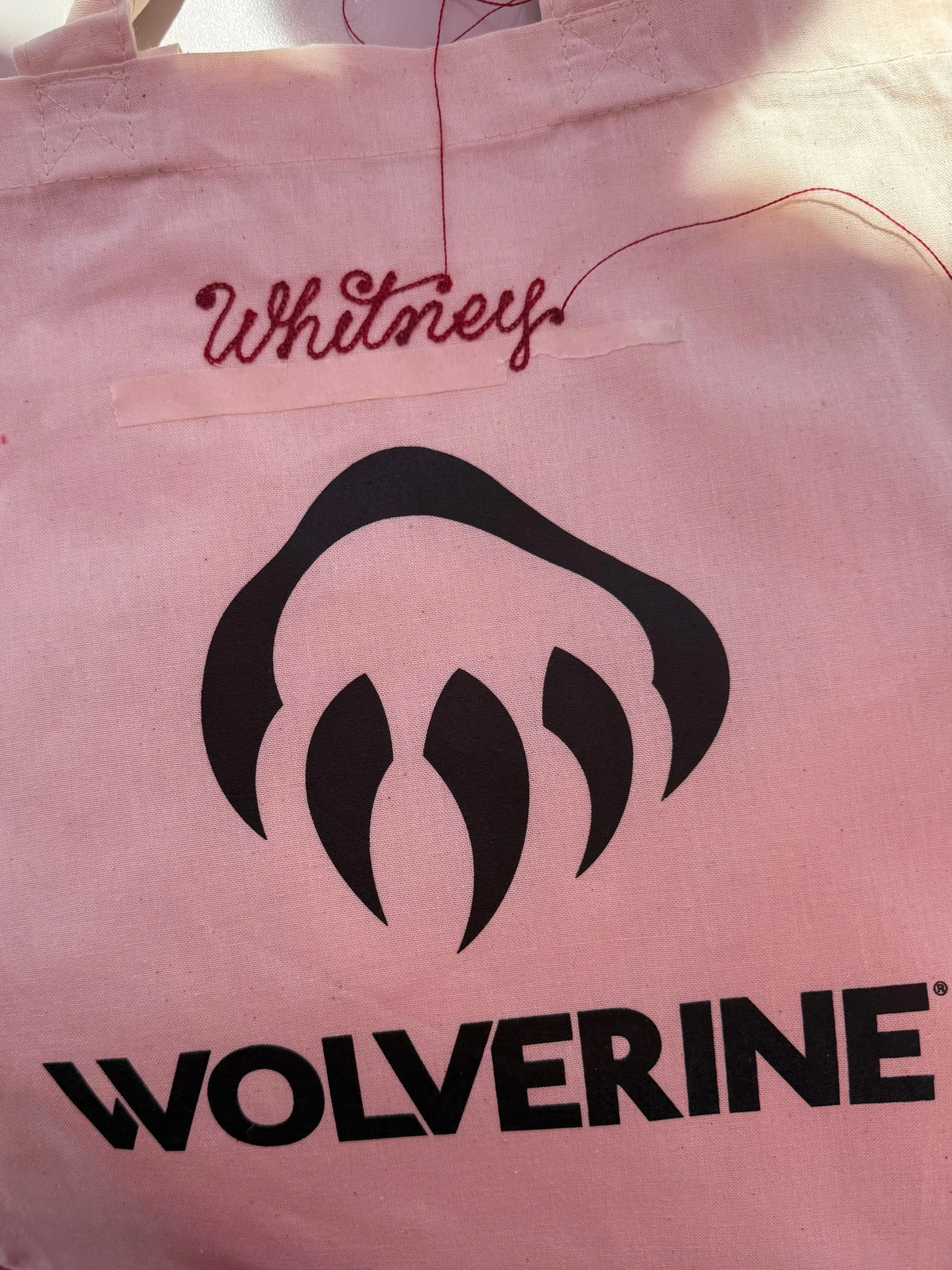Cnvas tote bag with the Wolverine logo in black and the name Whitney embroidered in cursive embroidery.