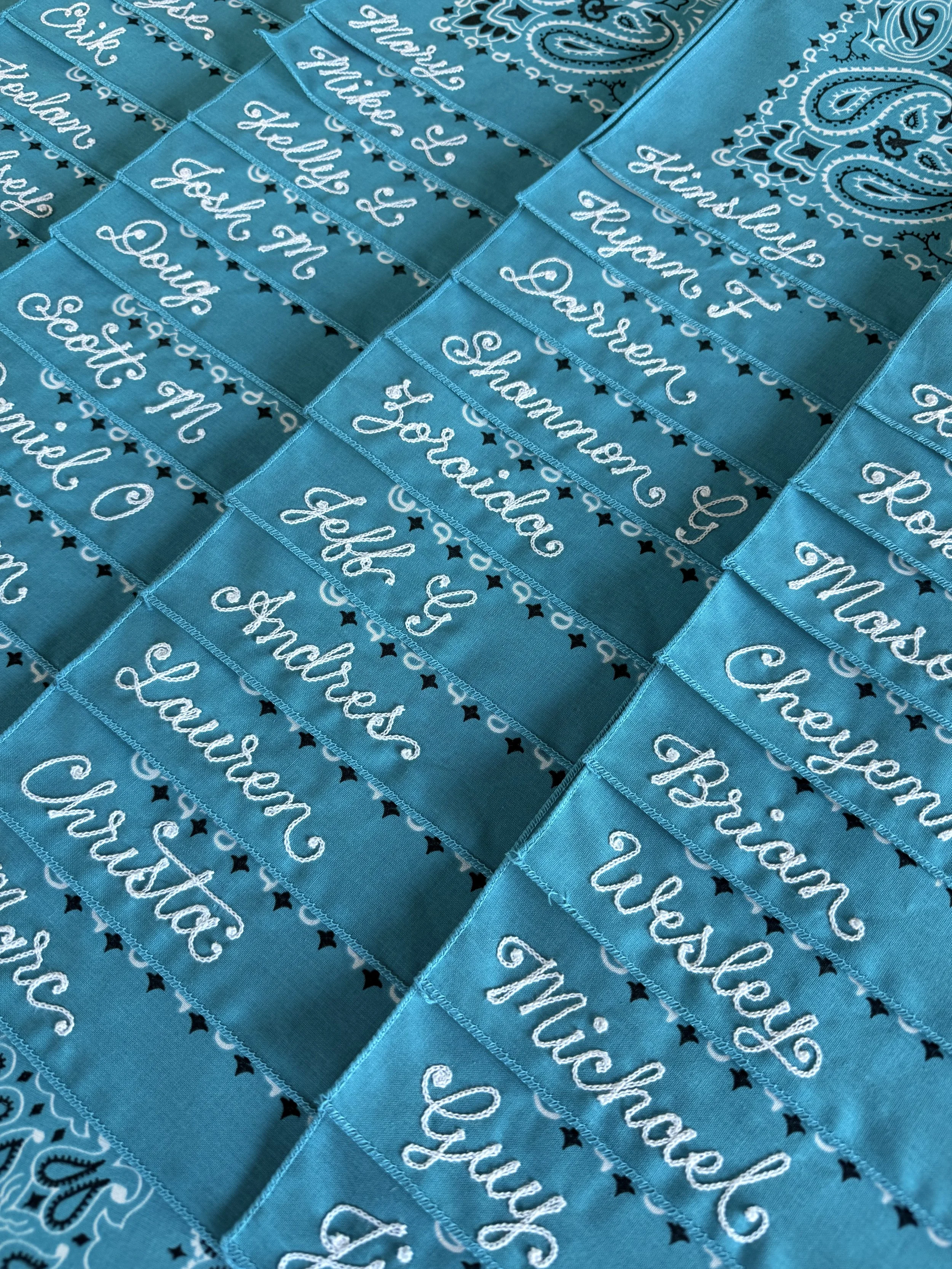 Bulk bandana order with chainstitch embroidered names. Teal bandanas, white thread.