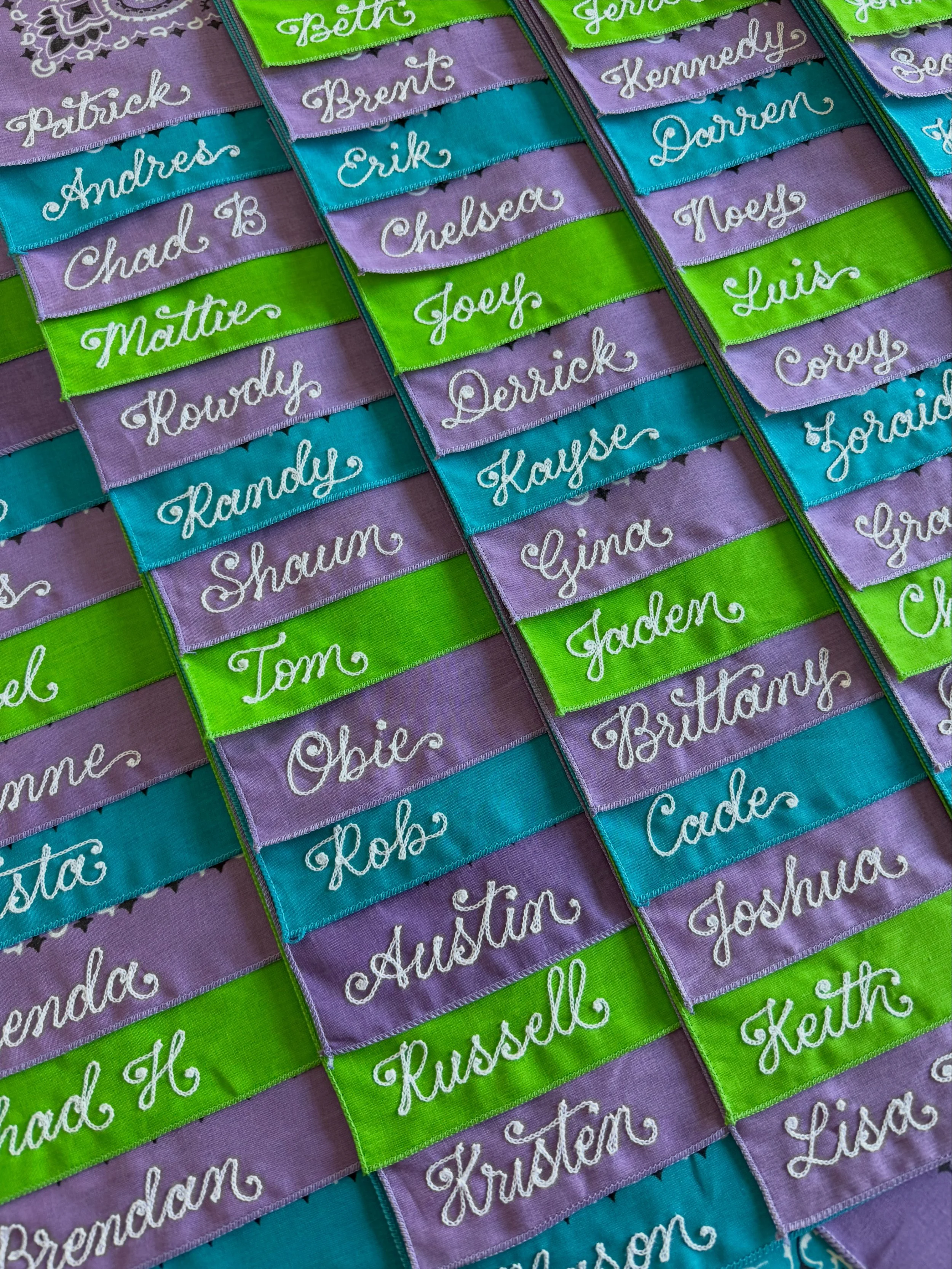 Colorful bandanas with chainstitch embroidered names in white thread.