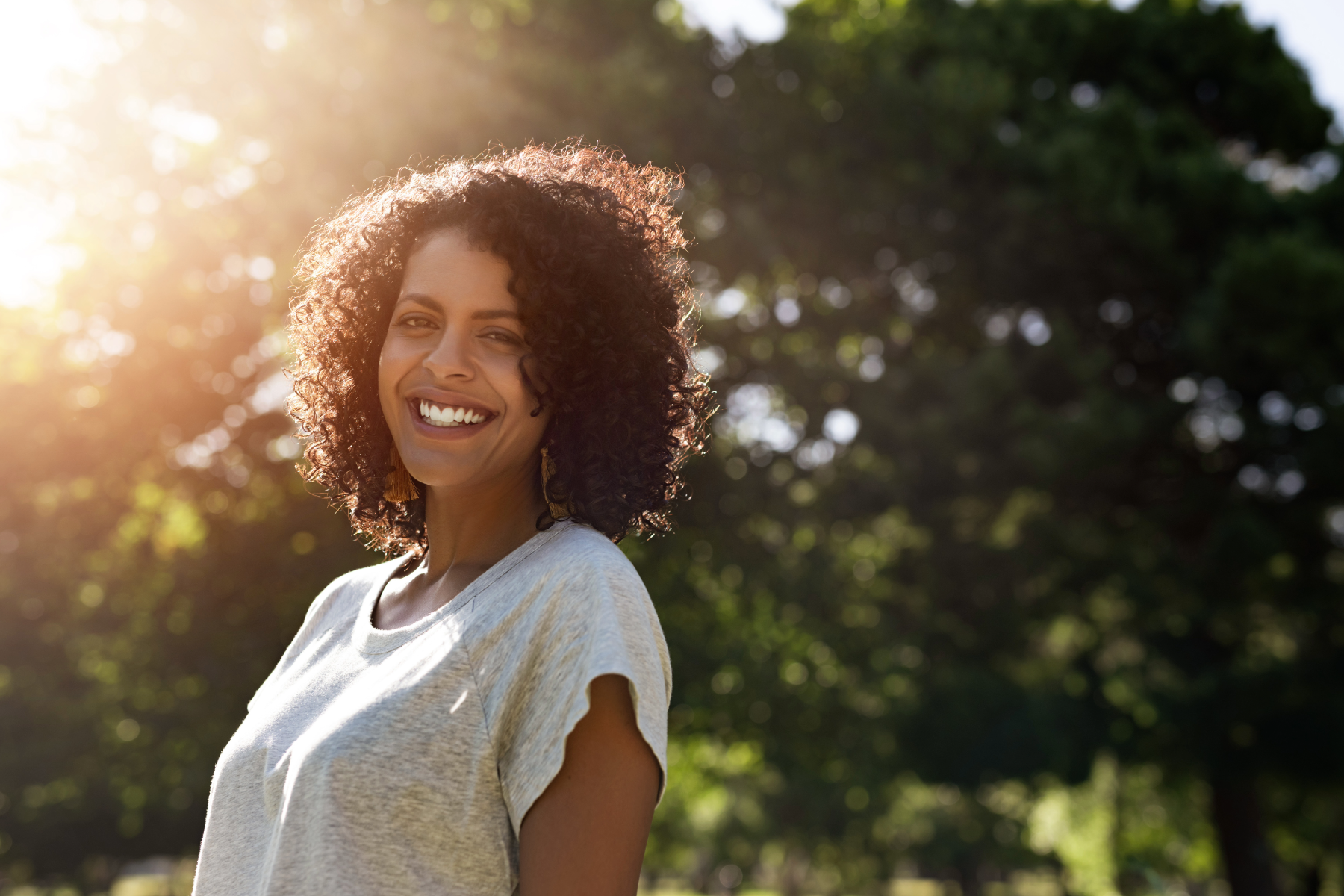 a person smiling at the camera while in the sunlight