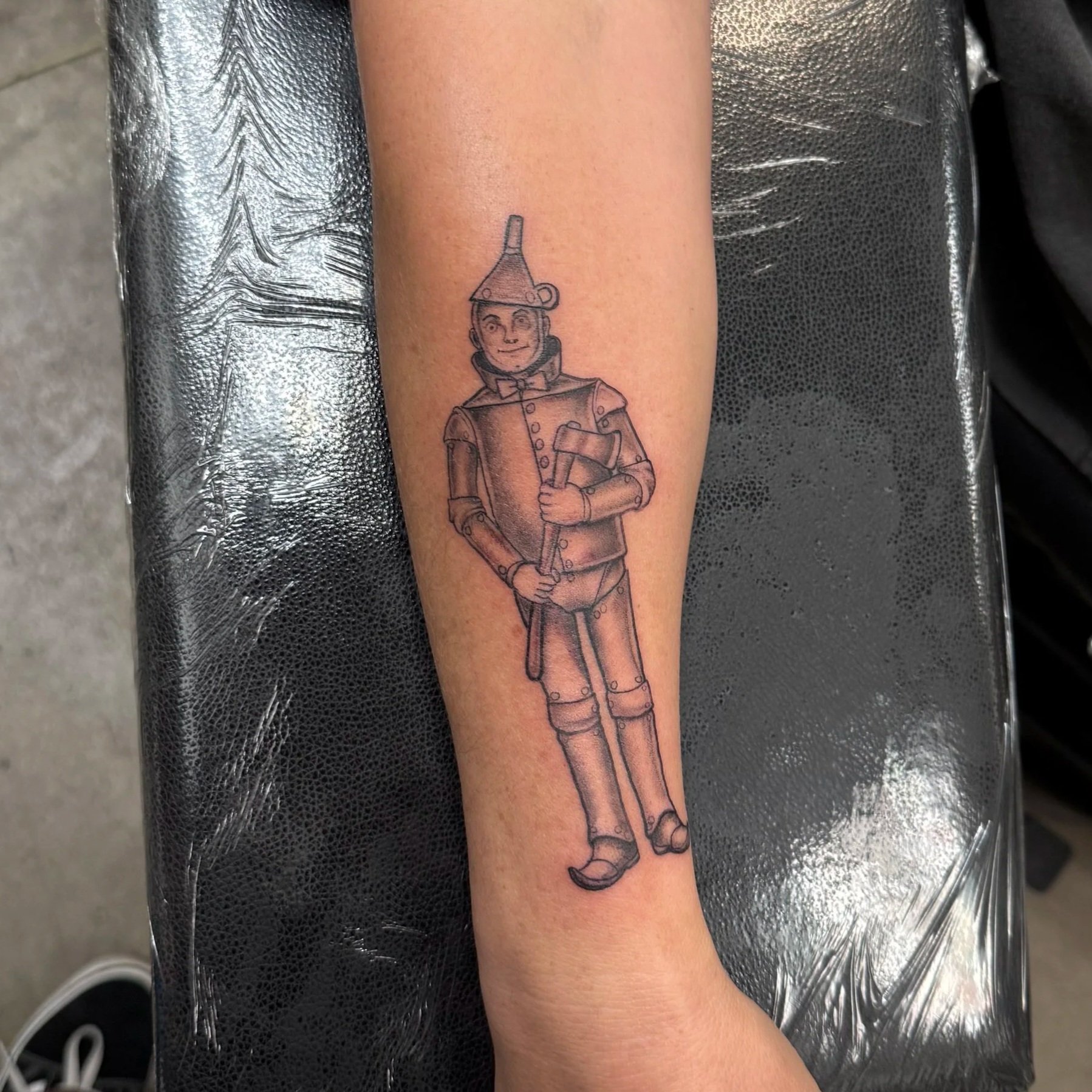 A tattoo of a vintage toy soldier in a marching pose on a person's arm, with the soldier wearing a tall hat, uniform, and holding a rifle.