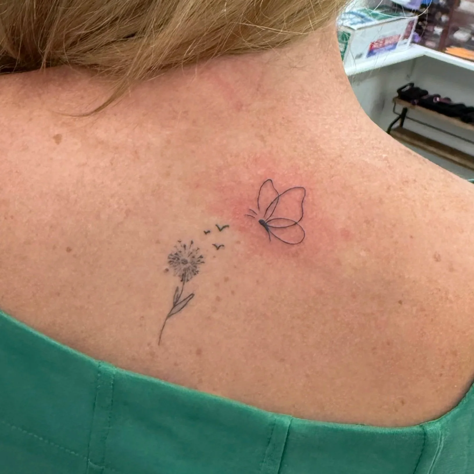 Close-up of a person's shoulder with a tattoo of a dandelion, butterfly, and flying birds. Tattoo by Elizabeth Guerrero at Austin Texas Tattoos in 2026