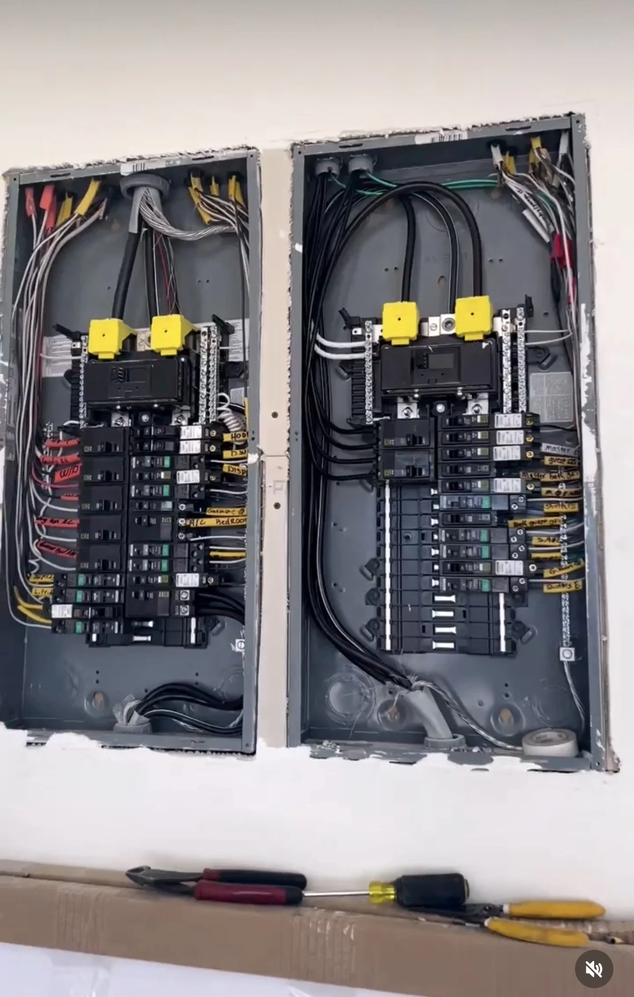 Open electrical breaker panels with wire connections and labels. Tools like screwdrivers and pliers are placed below the panels.