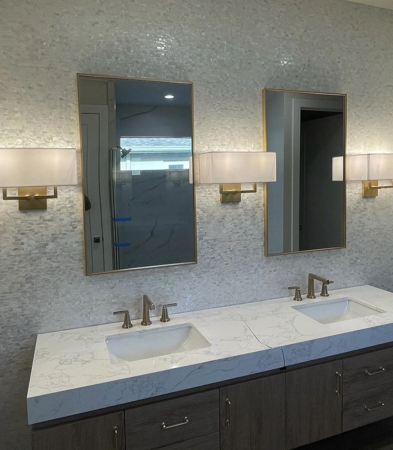 Bathroom with a double vanity, marble countertop, two rectangular sinks, two mirrors, and three wall-mounted lights.