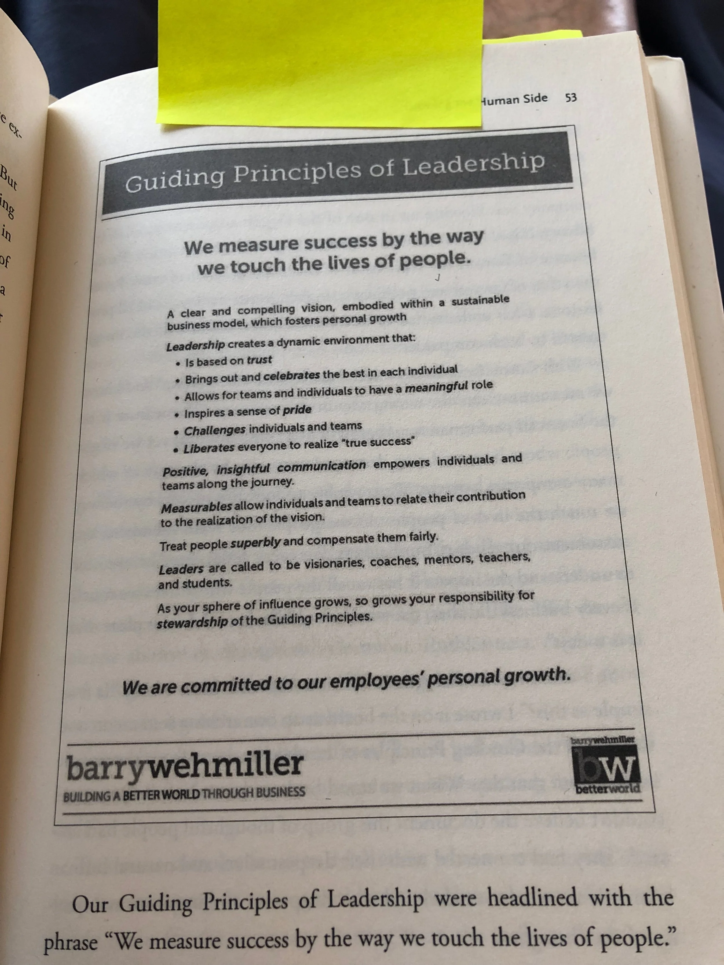 A page from a book titled "Guiding Principles of Leadership" with text about leadership values, including trust, pride, communication, and stewardship, and the quote "We measure success by the way we touch the lives of people." There is a yellow stic