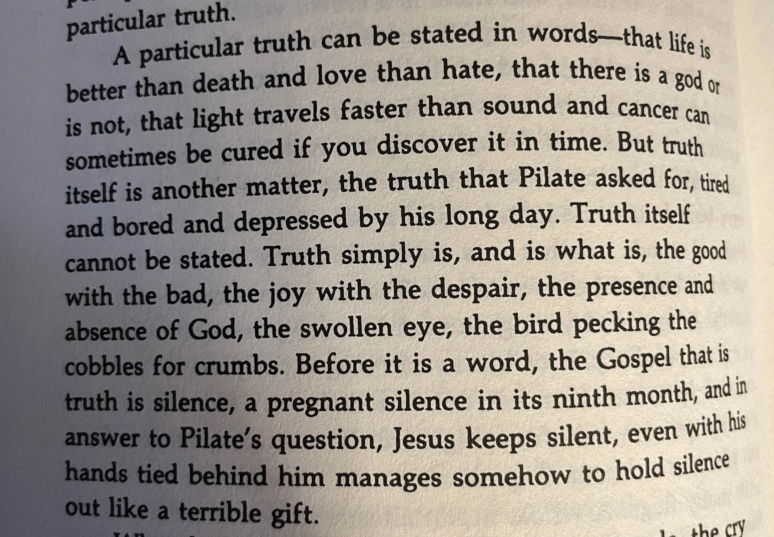 Close-up of a book page with printed text discussing the nature of truth, love, hate, and the silence of Jesus.