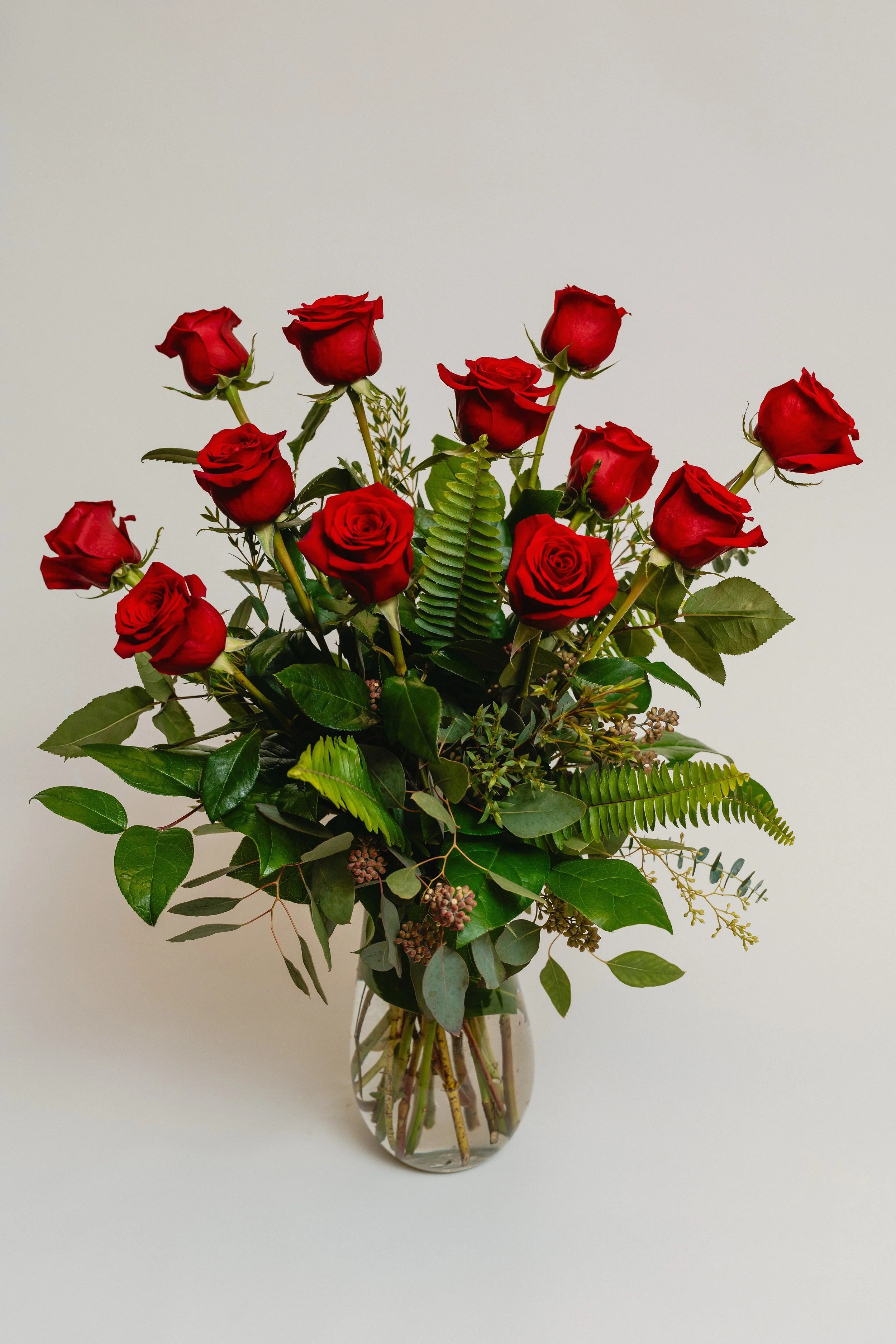 One dozen roses with premium assorted greenery in a glass vase. $159.95