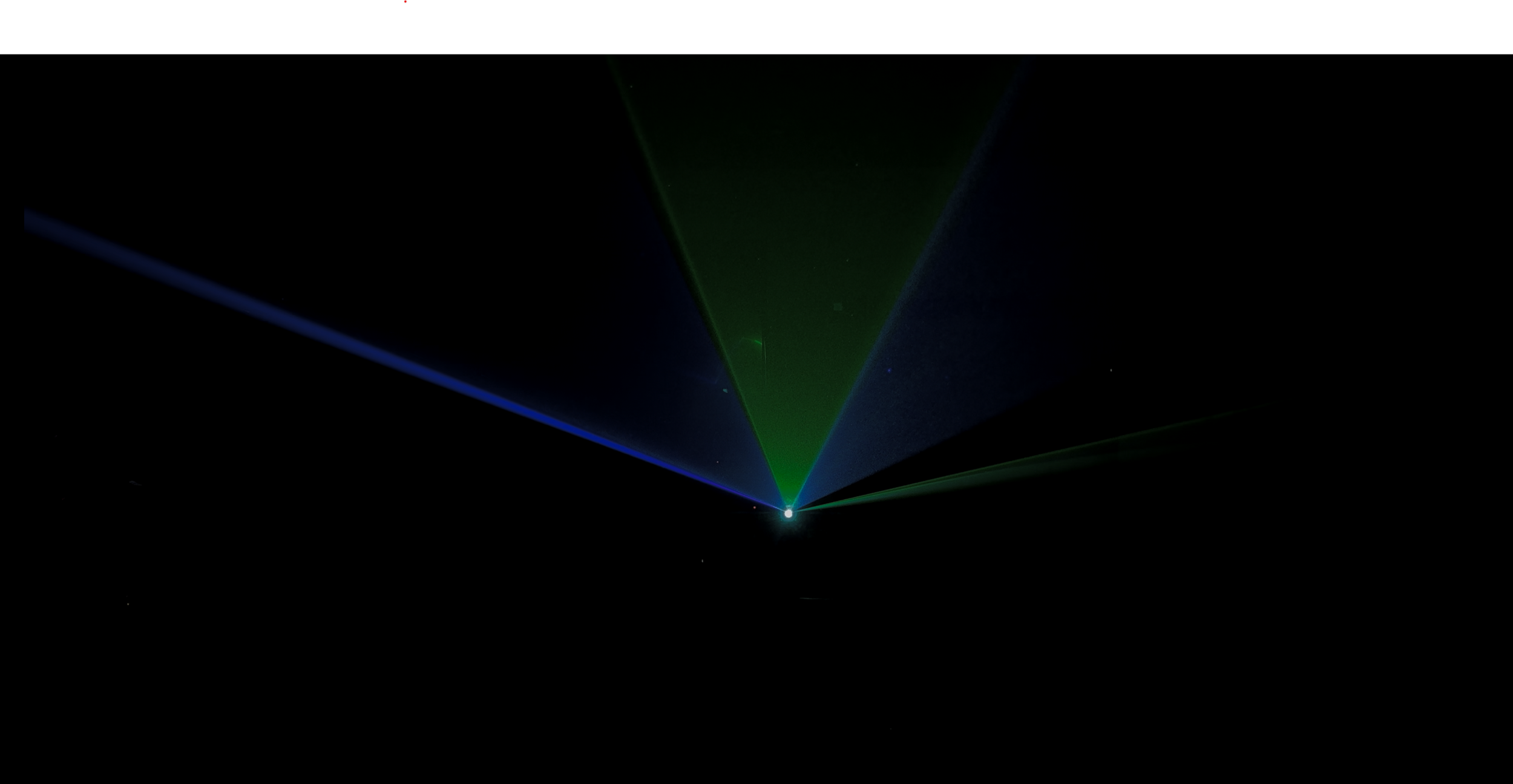 Green, blue, and red laser beams projected in the dark sky from a single point.