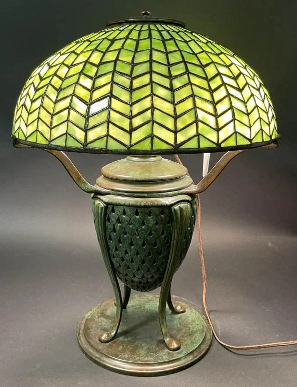 Antique table lamp with a green stained glass shade and ornate metal base.