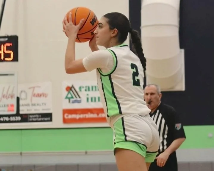 Basketball player in white and green jersey preparing to shoot