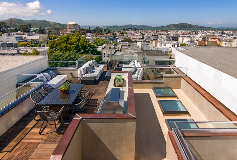 Rooftop terrace with outdoor furniture, dining table, and panoramic city view.