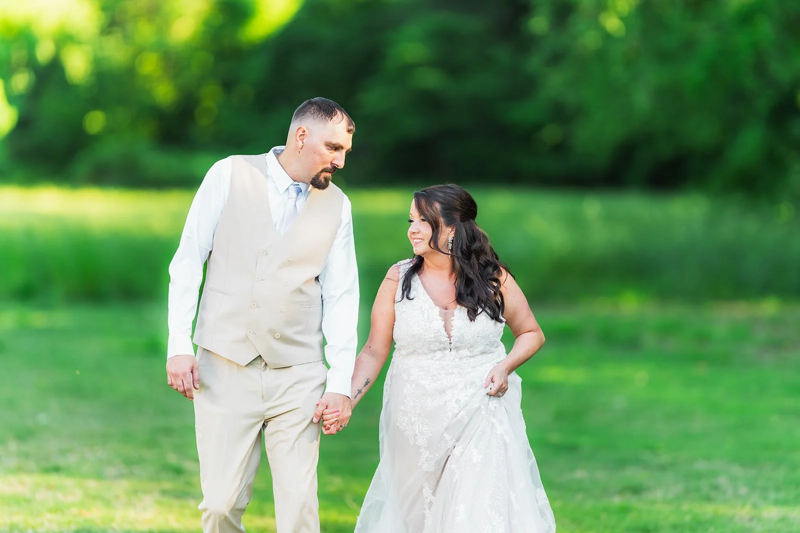 bride and groom walking in the grass at White Oak Farms in Medina, TN