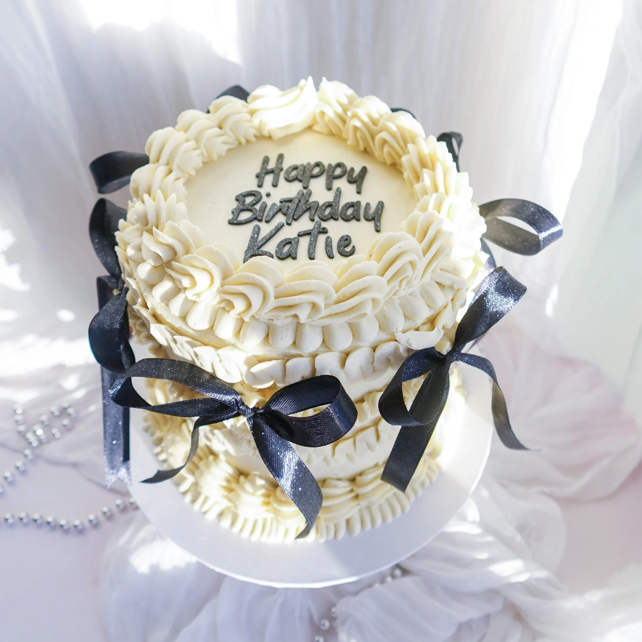 Black bows, vintage piping, and buttercream so smooth it deserves its own fan club 🎀🖤

Keeping it classic with white buttercream, choc mud cake &amp; caramel sauce layers and all the birthday magic for Katie ✨

Would you choose black &amp; white fo