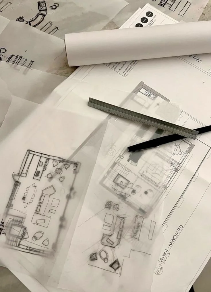 Architectural blueprints and sketches of room layouts with a ruler and a pen on top.