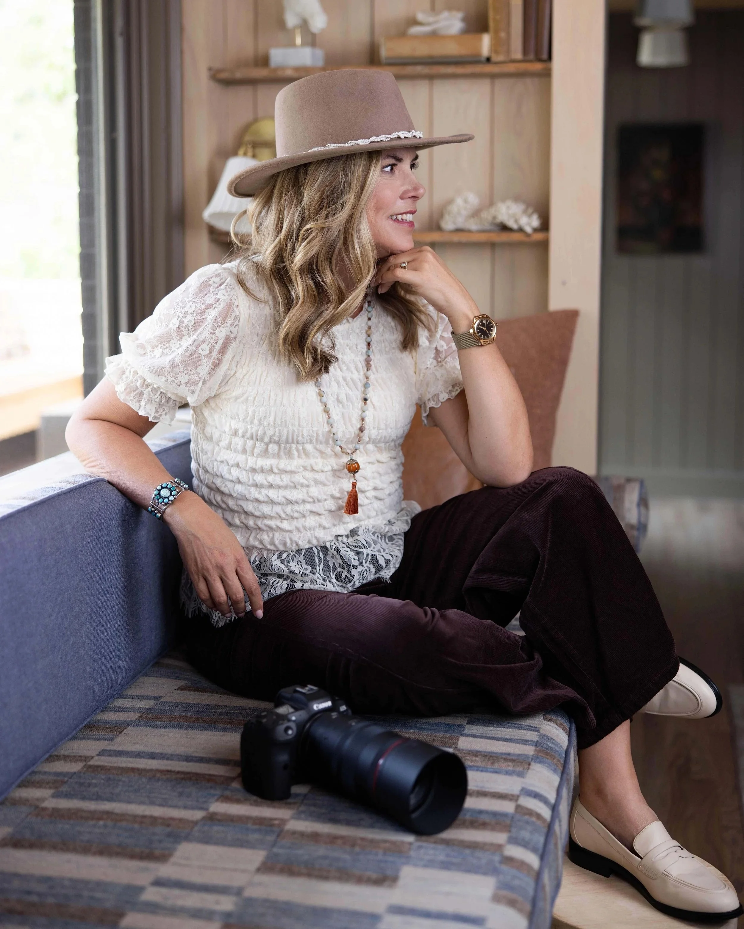 Kim Brundage wearing an ivory lace top thinking about the future with her camera.