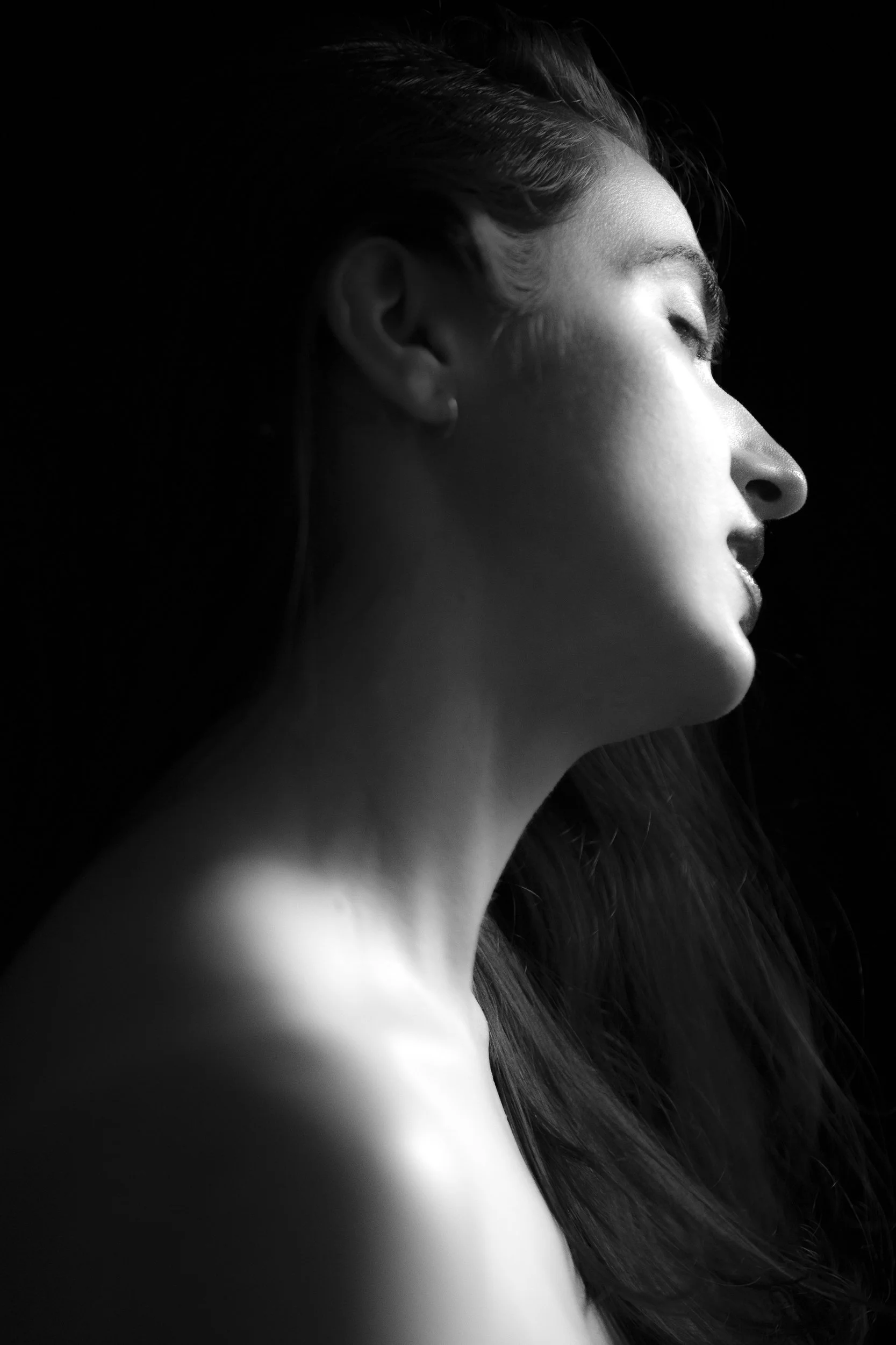 Black and white profile of a woman with closed eyes and long hair, illuminated by soft light.