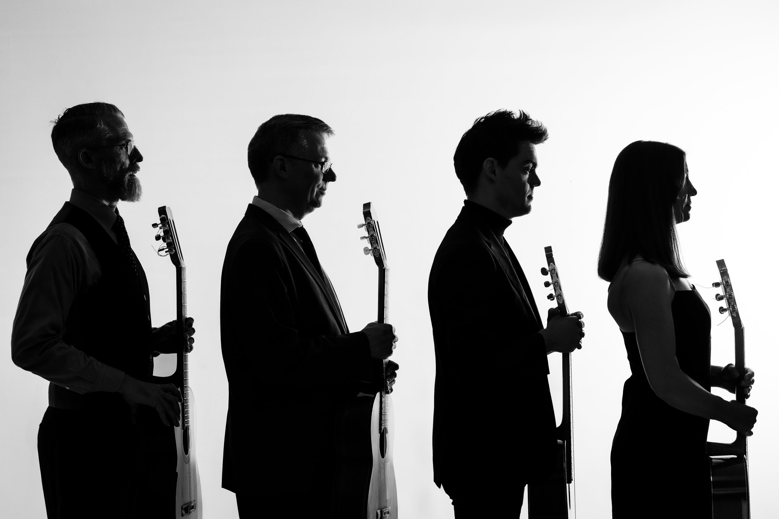 Silhouette of four people standing in profile, each holding a guitar.