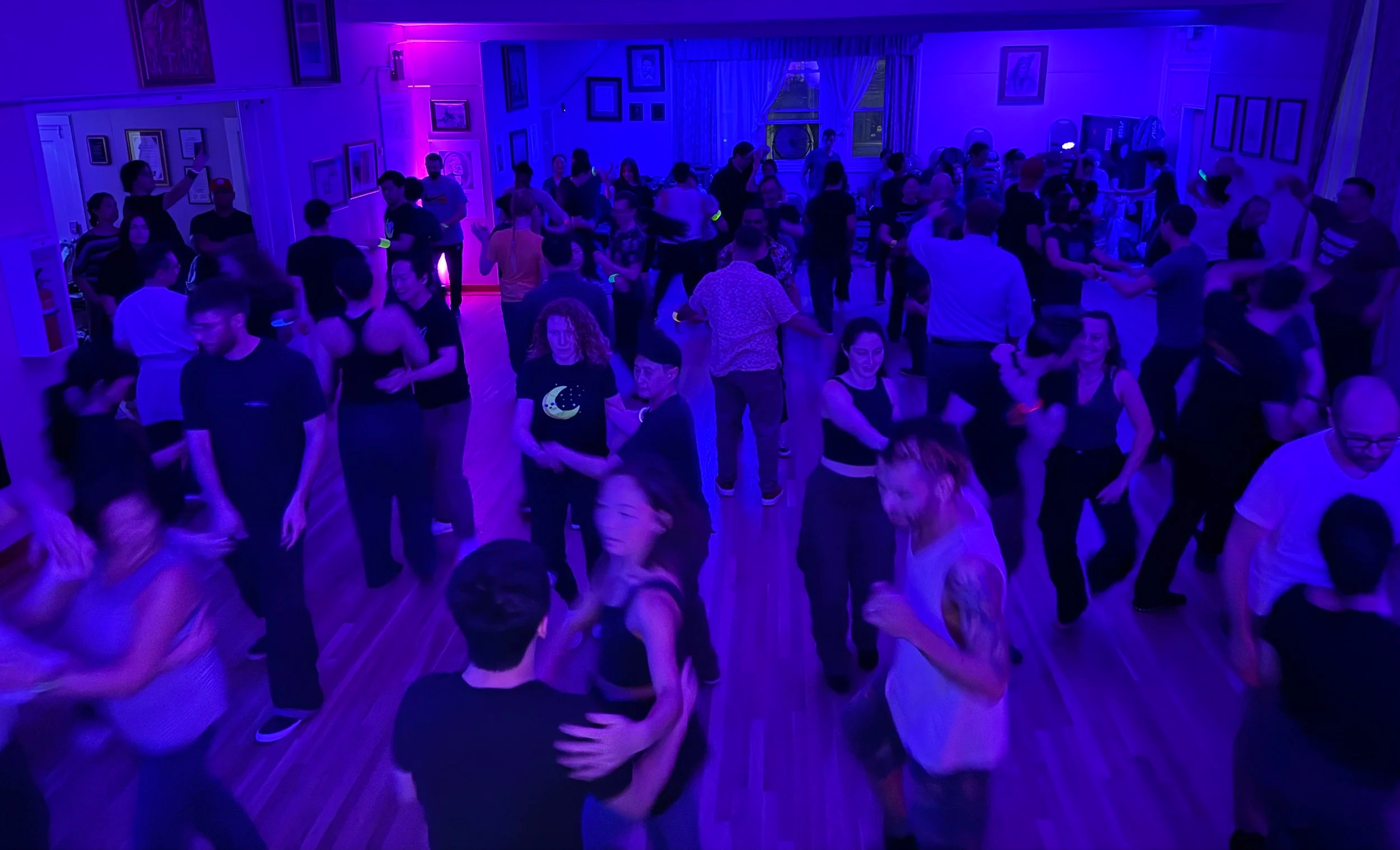 People dancing in a dimly lit room with purple and blue lighting.