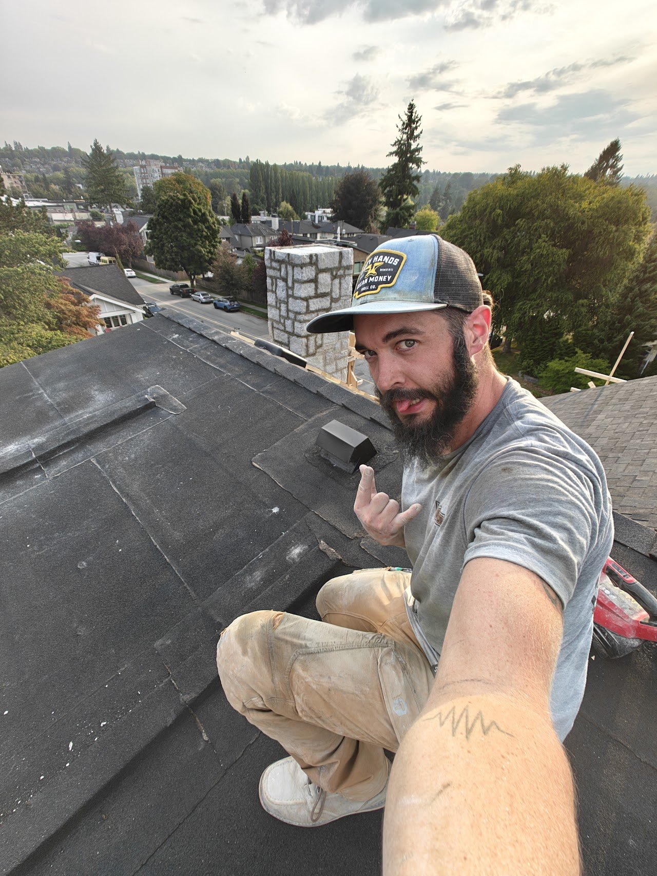 Stone mason on a roof facing a chimney. Chimney veneer install
