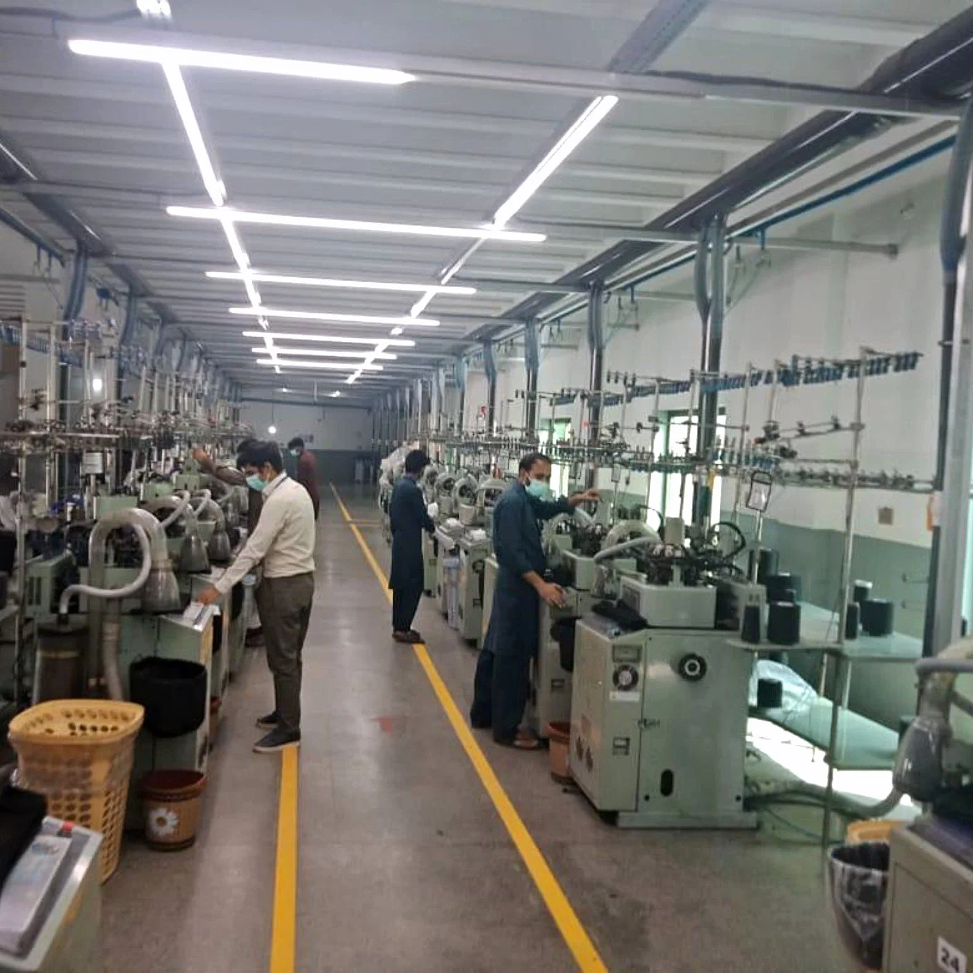 Operators at single-cylinder sock knitting machines in the Socks House factory, Faisalabad, Pakistan