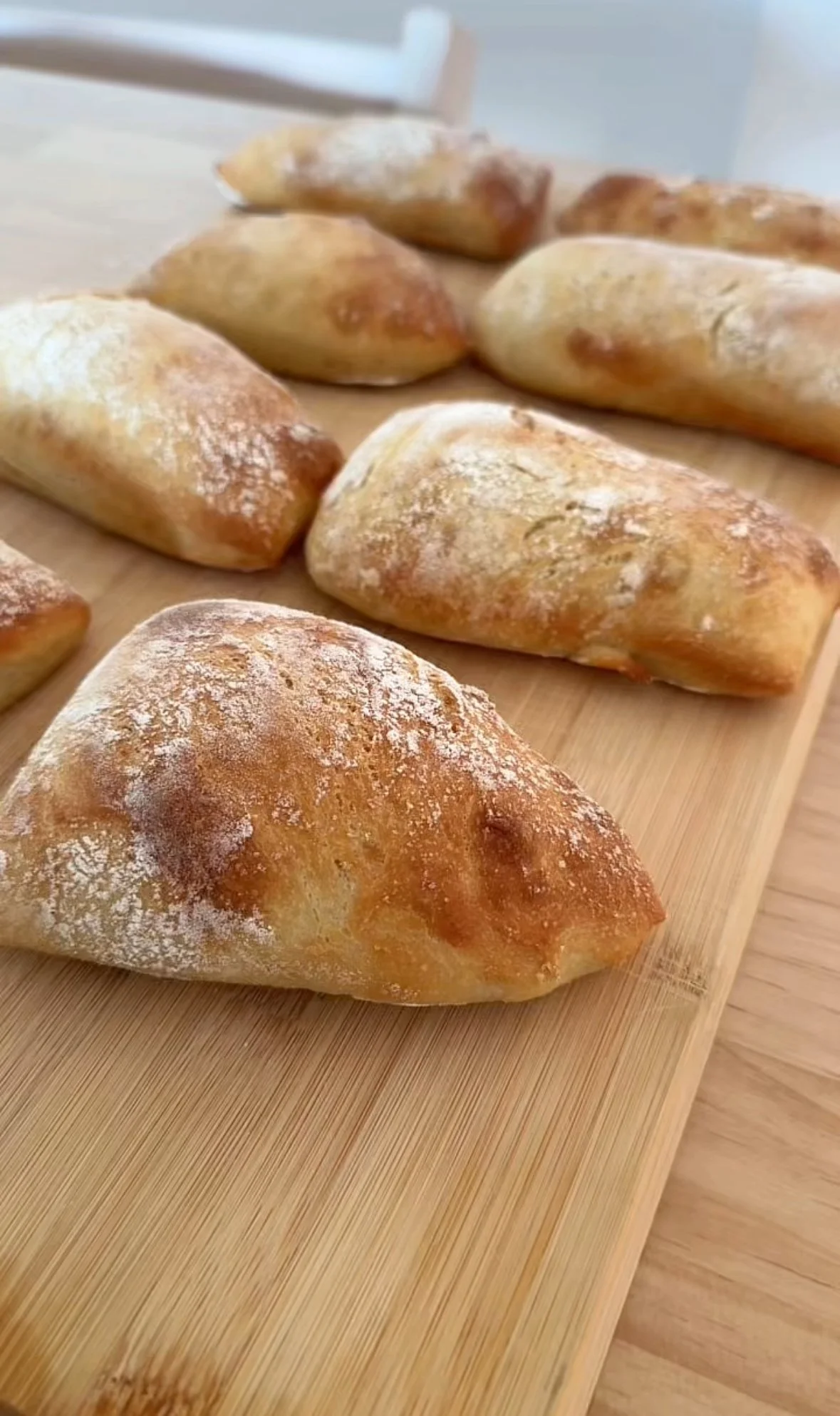 Freshly baked Italian calzones with golden crust and a light dusting of flour on a wooden cutting board.