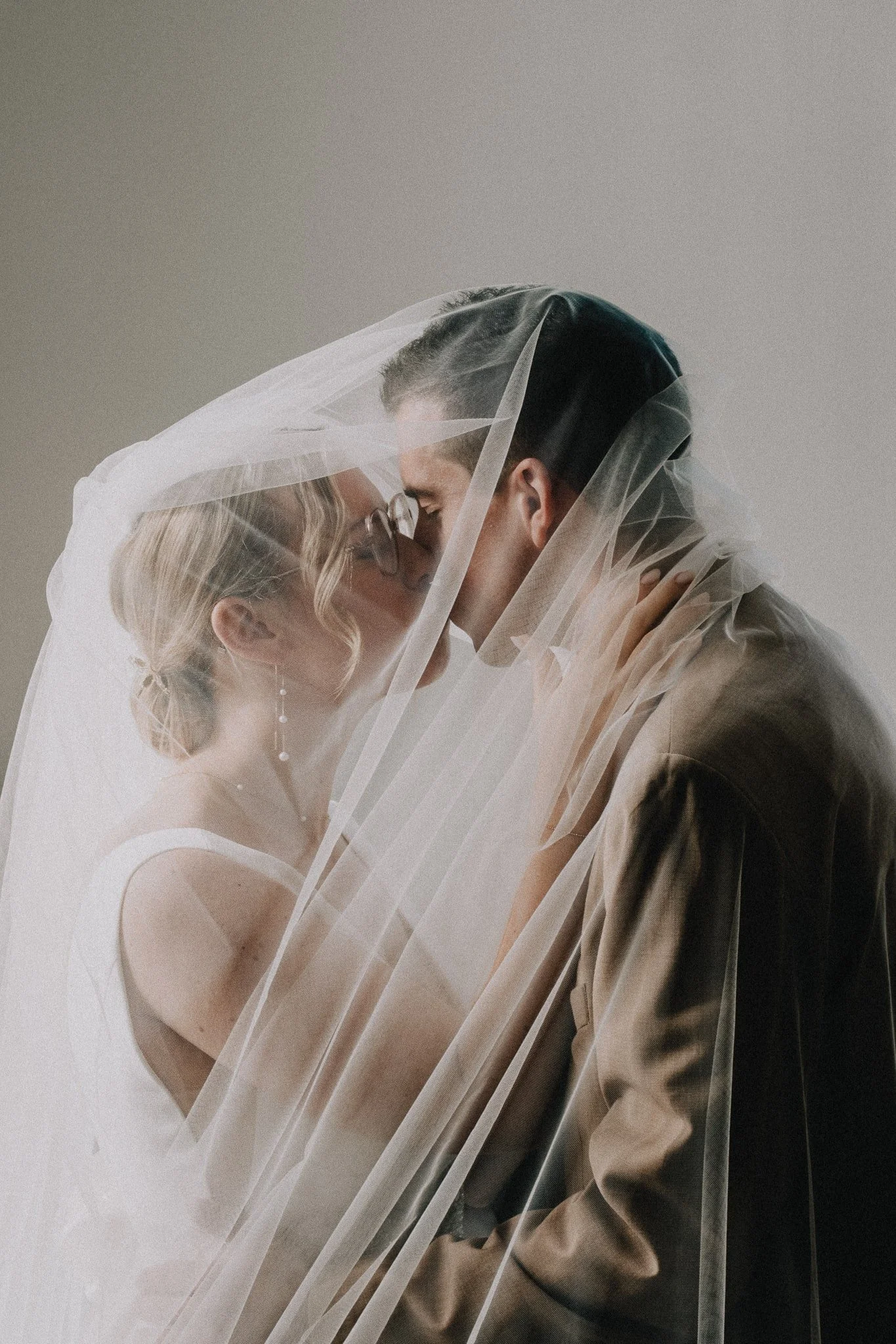 A bride and groom sharing a kiss under a veil.