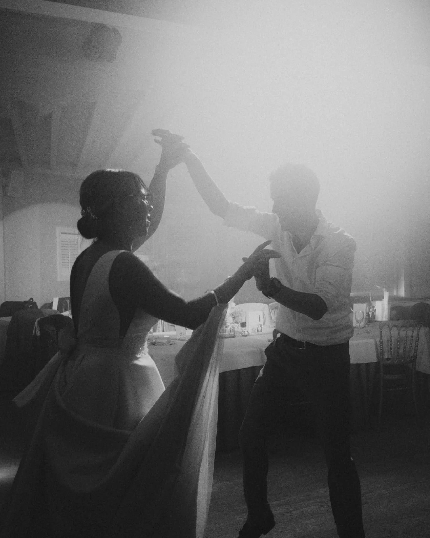 Zwart-wit foto van een koppel dat hand in hand danst tijdens hun huwelijk, artistieke huwelijksfotografie door Jasper Nevel