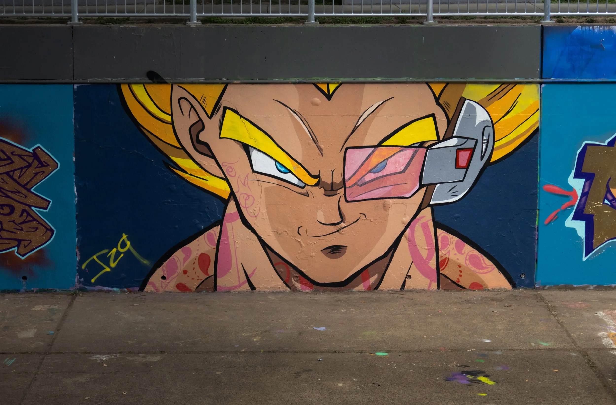 Graffiti mural of Trunks from Dragon Ball Z with blonde hair, wearing a visor, smirking, on a city wall.