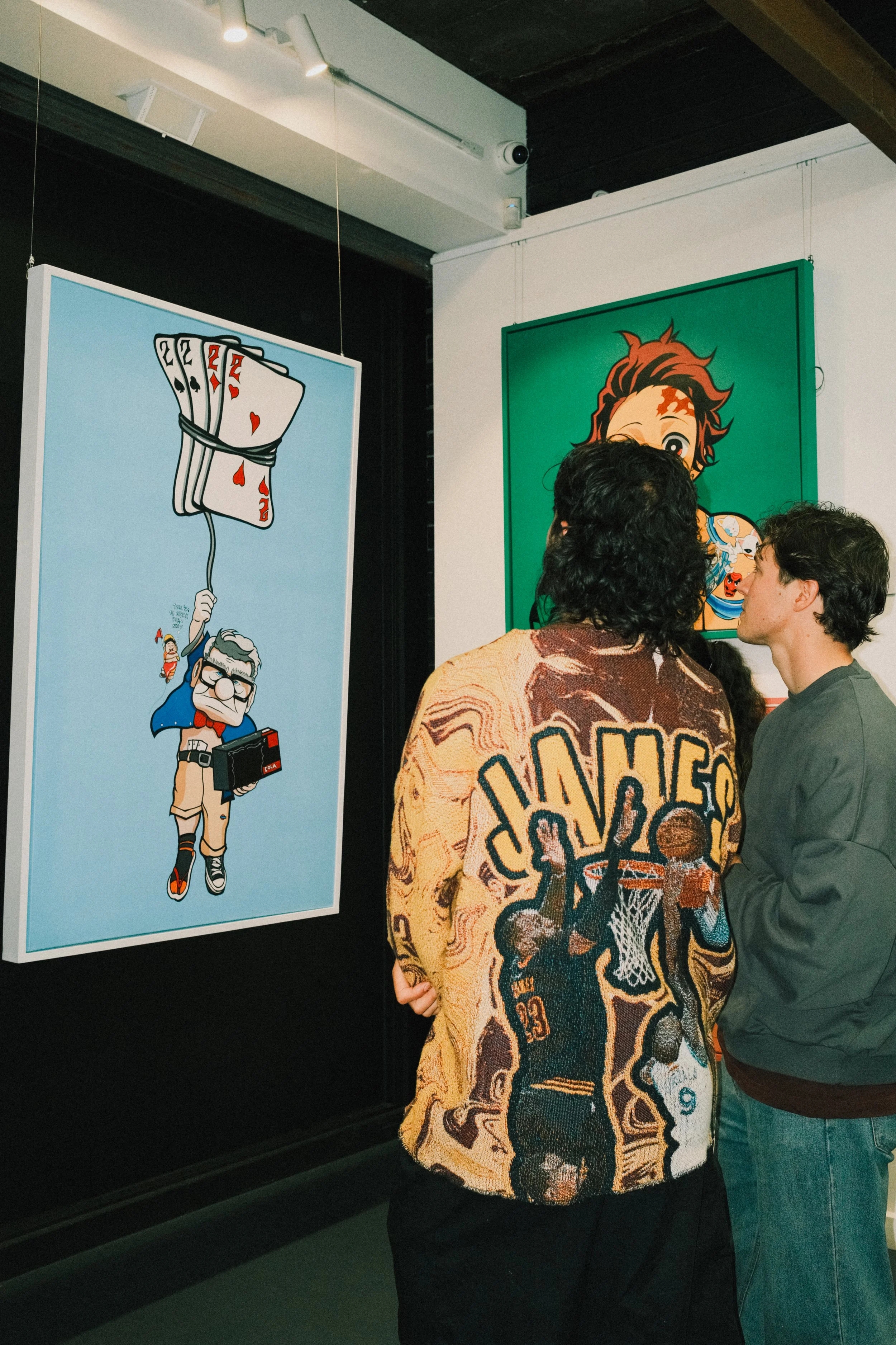 People viewing colorful pop art paintings at an art gallery.