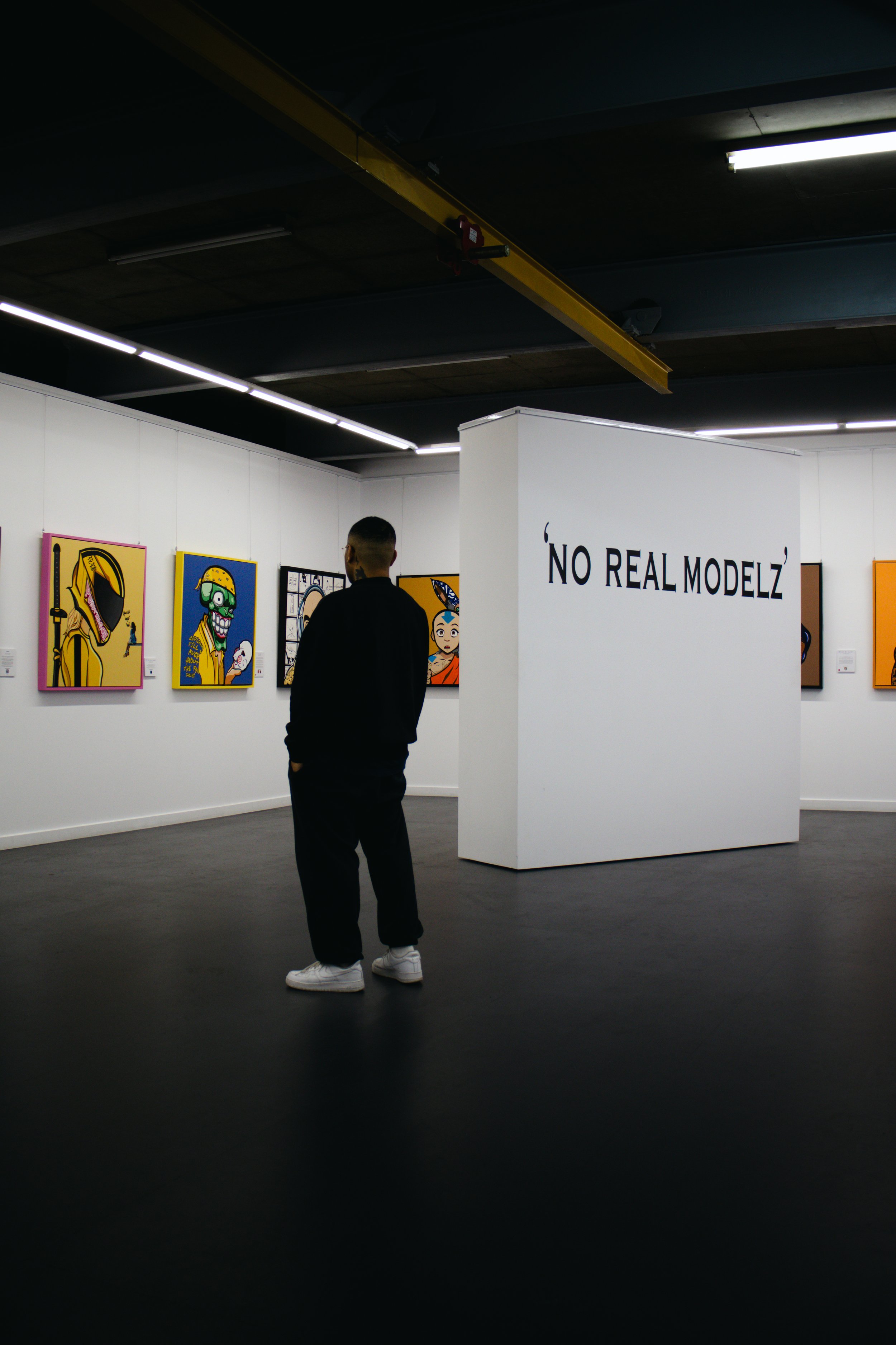 Person observing art at an exhibition titled 'NO REAL MODELZ'.