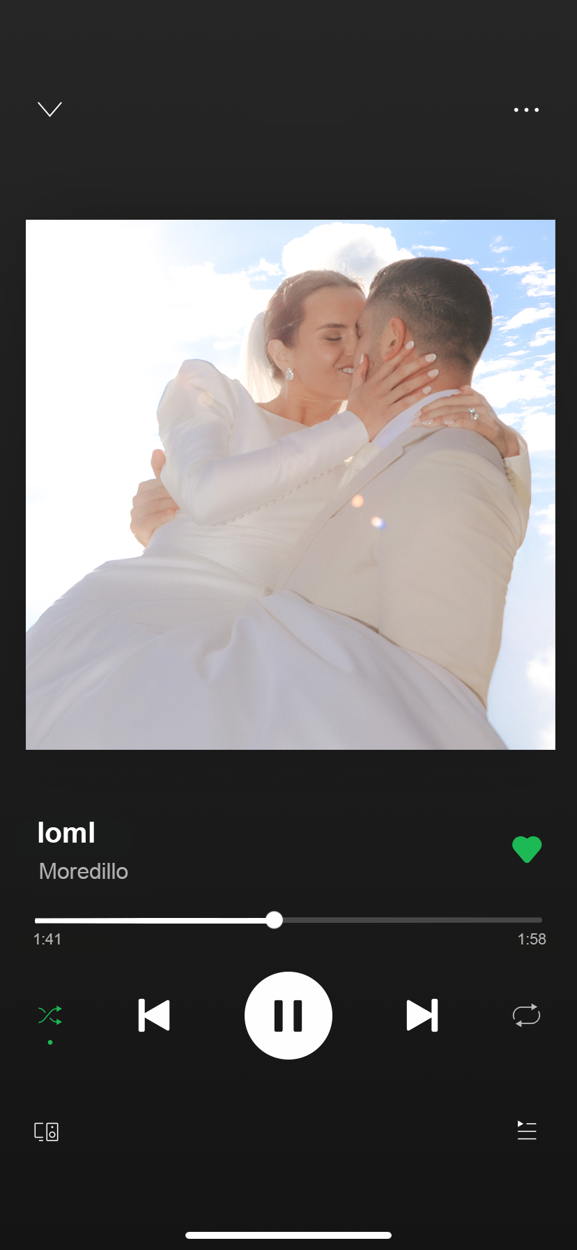 A newlywed couple sharing a kiss outdoors with a bright sky and clouds in the background.