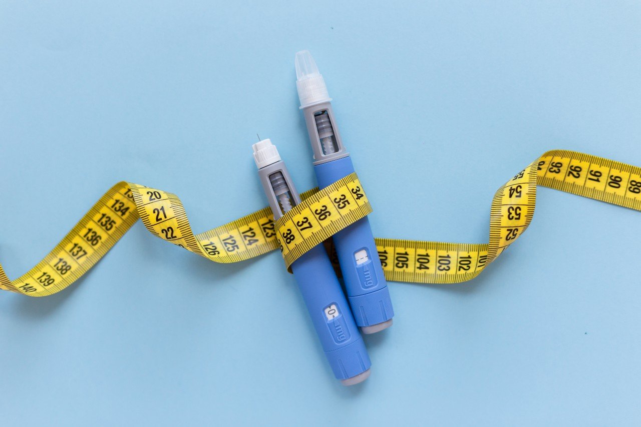 two-injectors-of-anti-obesity-medication-wrapped-with-measuring-tape-on-blue-background.jpg