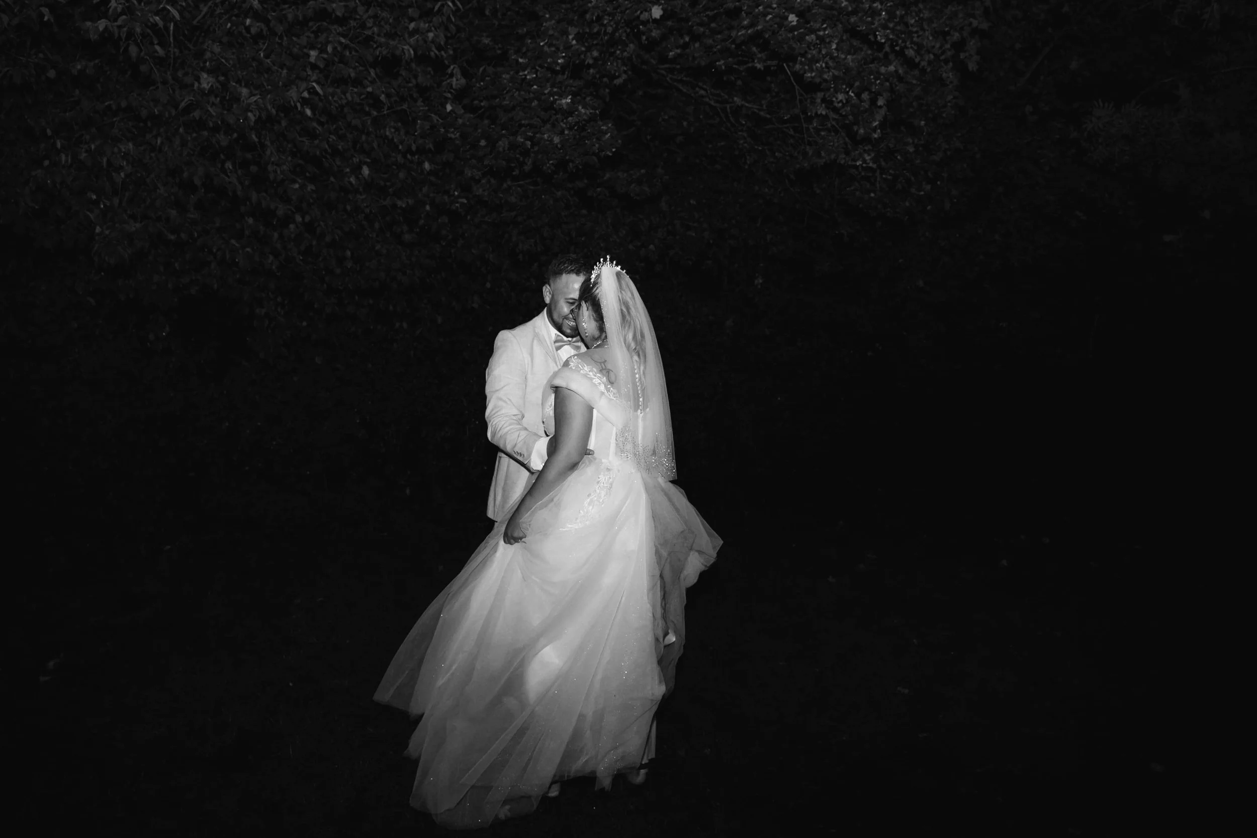 Braut und Bräutigam beim Tanz, schwarz-weiß Fotografie, intime Stimmung, Hochzeitskleidung, nächtliche Szene, romantisches Moment in freier Trauung