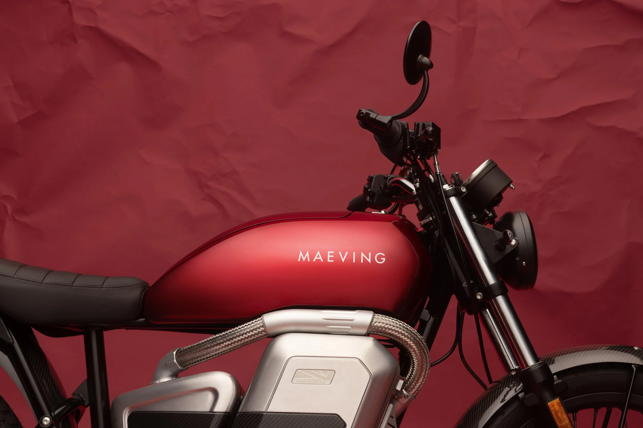 Une moto électrique de marque MAEVING et de couleur rouge avec des composants en métal et un siège noir.