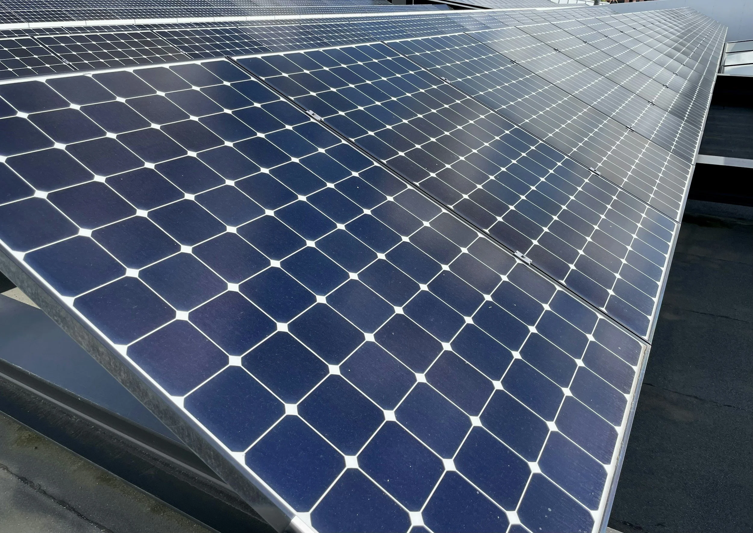 Close-up view of multiple solar panels installed on a rooftop, reflecting sunlight.