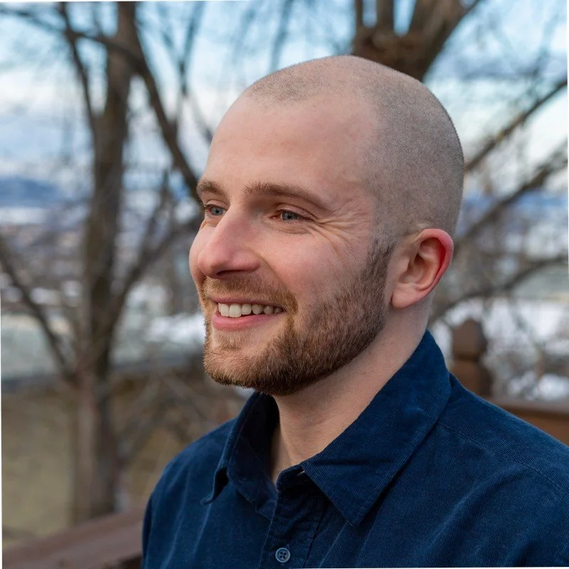 Matthew Parent, Principal Consultant, smiling and wearing a dark blue shirt, outdoors with trees in the background.