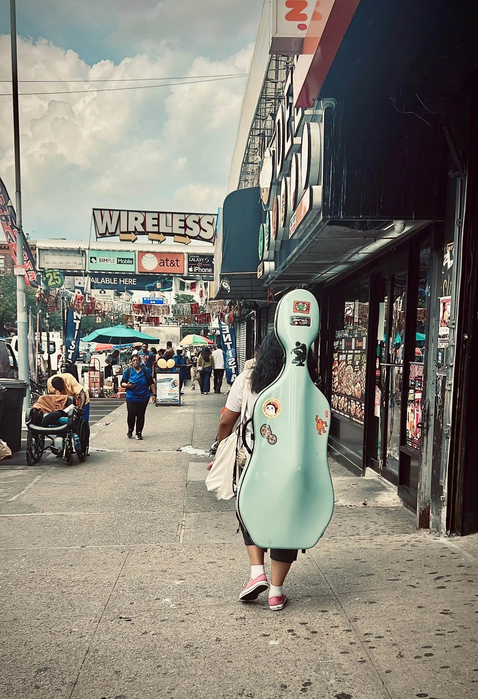 Instrument on the Street — a person carries an instrument case along a busy sidewalk
