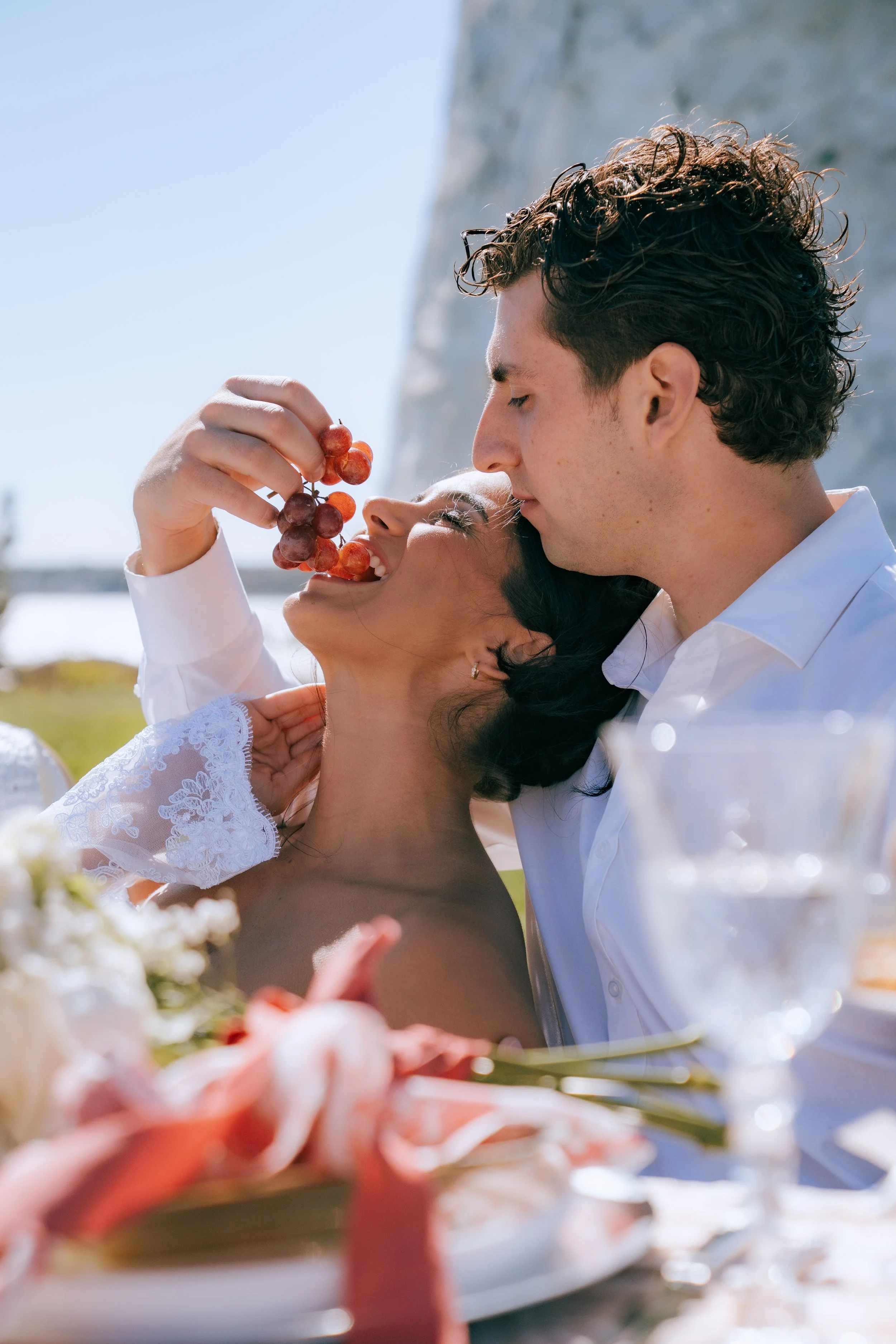 Romantic proposal picnic with champagne, florals, and ocean view backdrop